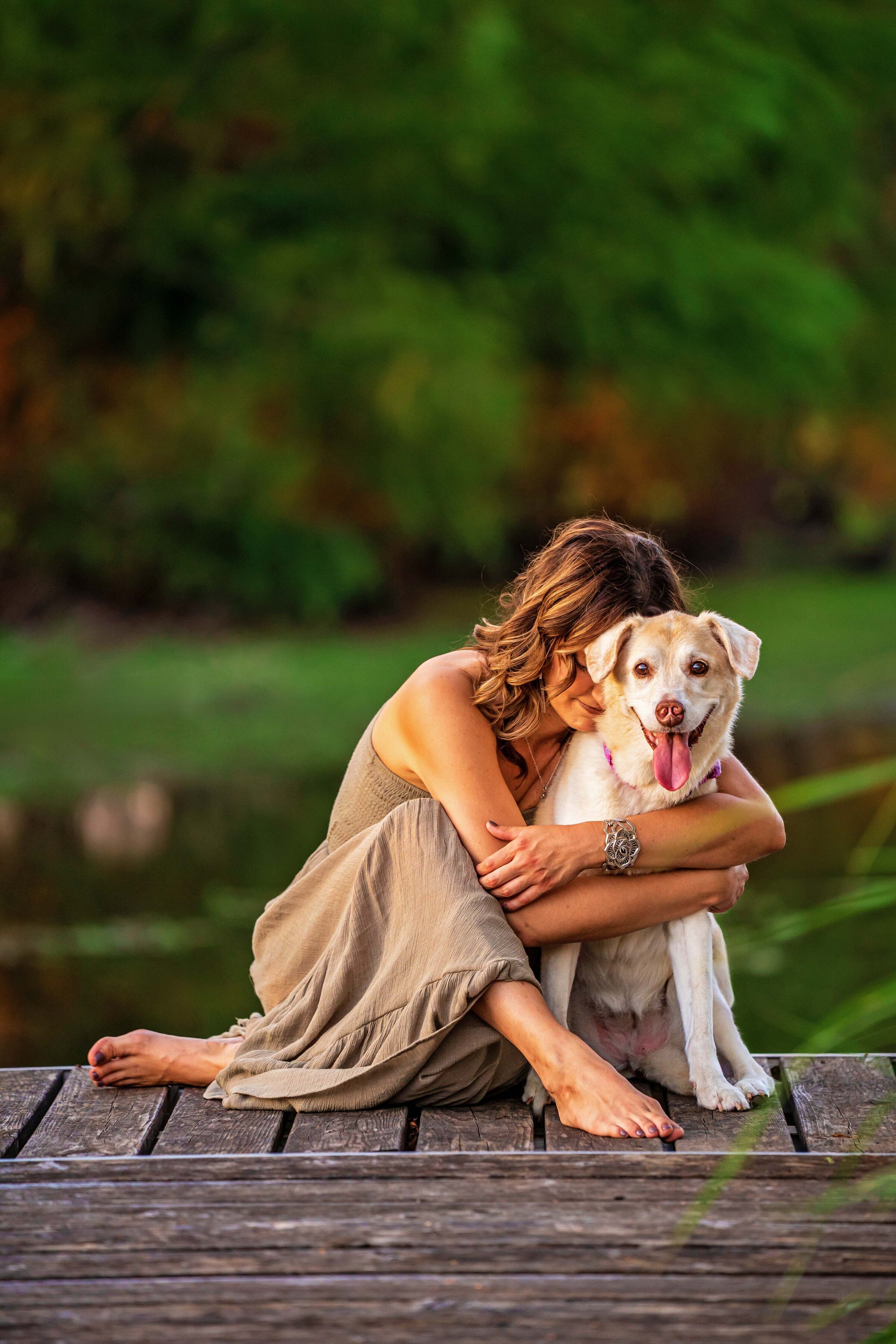 portrait of woman hugging dog on a dock