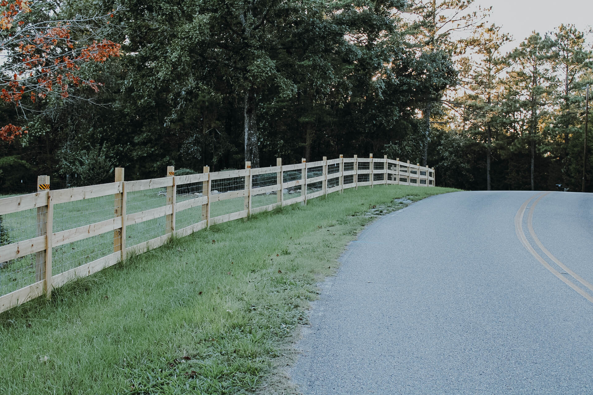 wooden-and-wire-fence-lining-edge-of-grassy-property-next-to-road