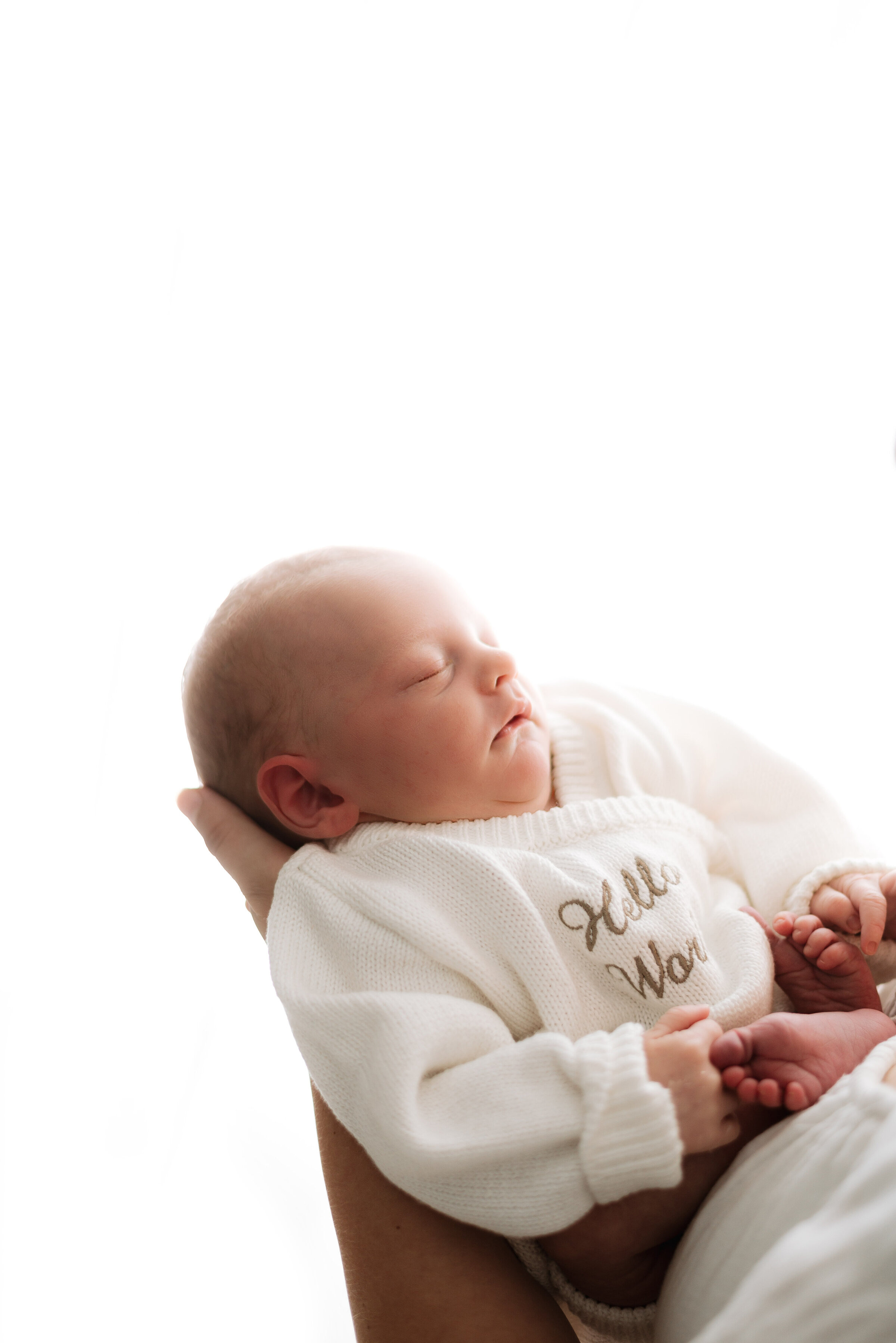 Newborn baby sleeping in mums arms with white background in newborn photoshoot in Billingshurst