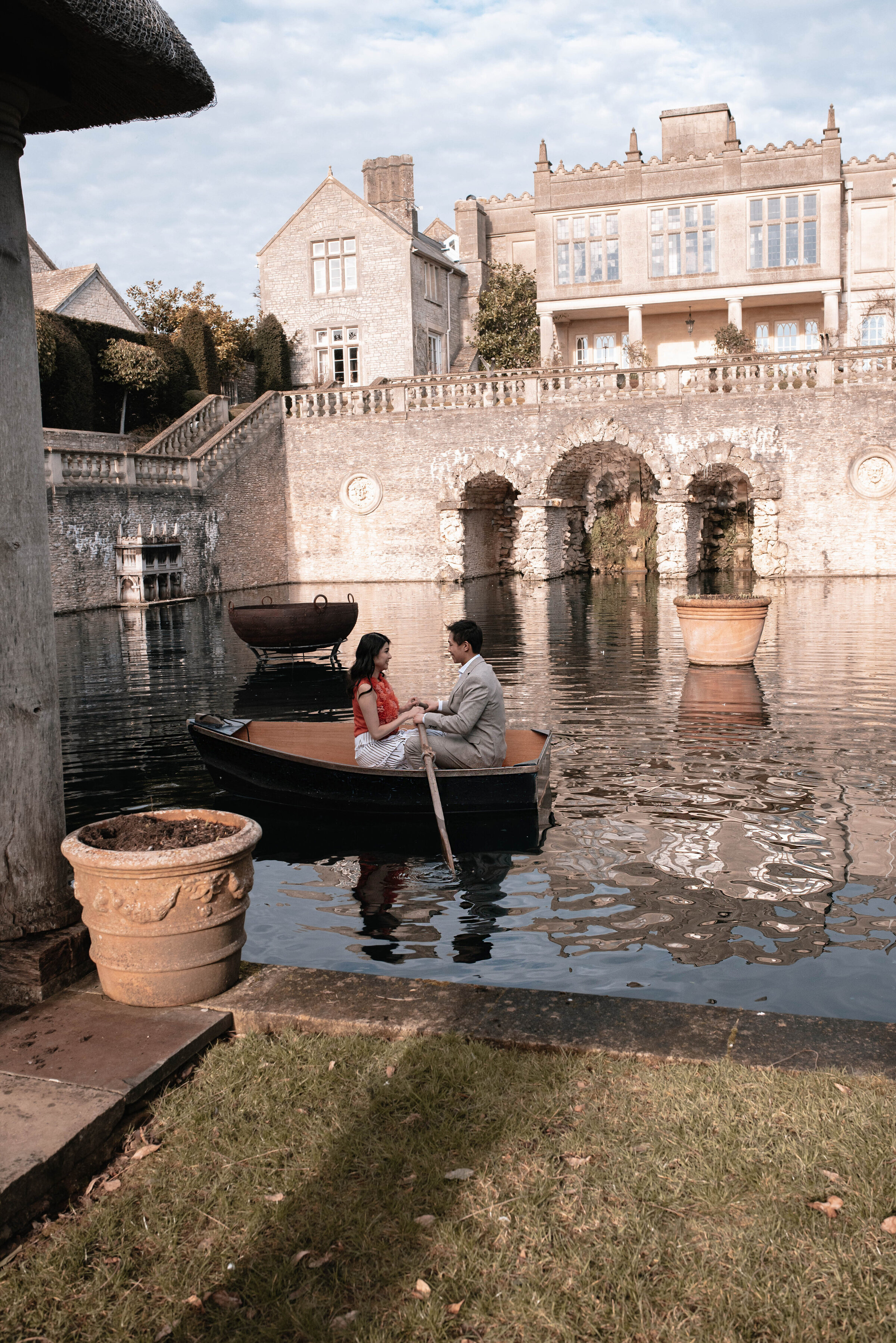 Man and woman on a small rowing boat in the middle of the pond at Euridge Manor wedding venue