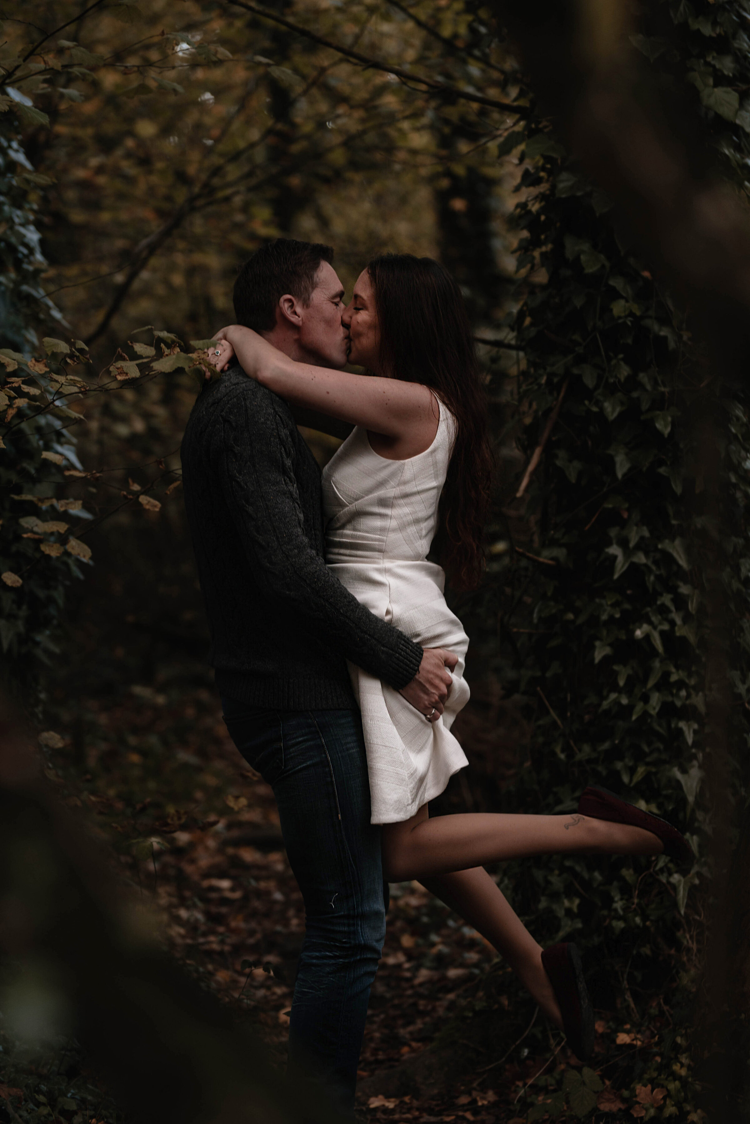 Man lifting woman into a kiss, she has one leg kicked out and her arms wrapped around his neck