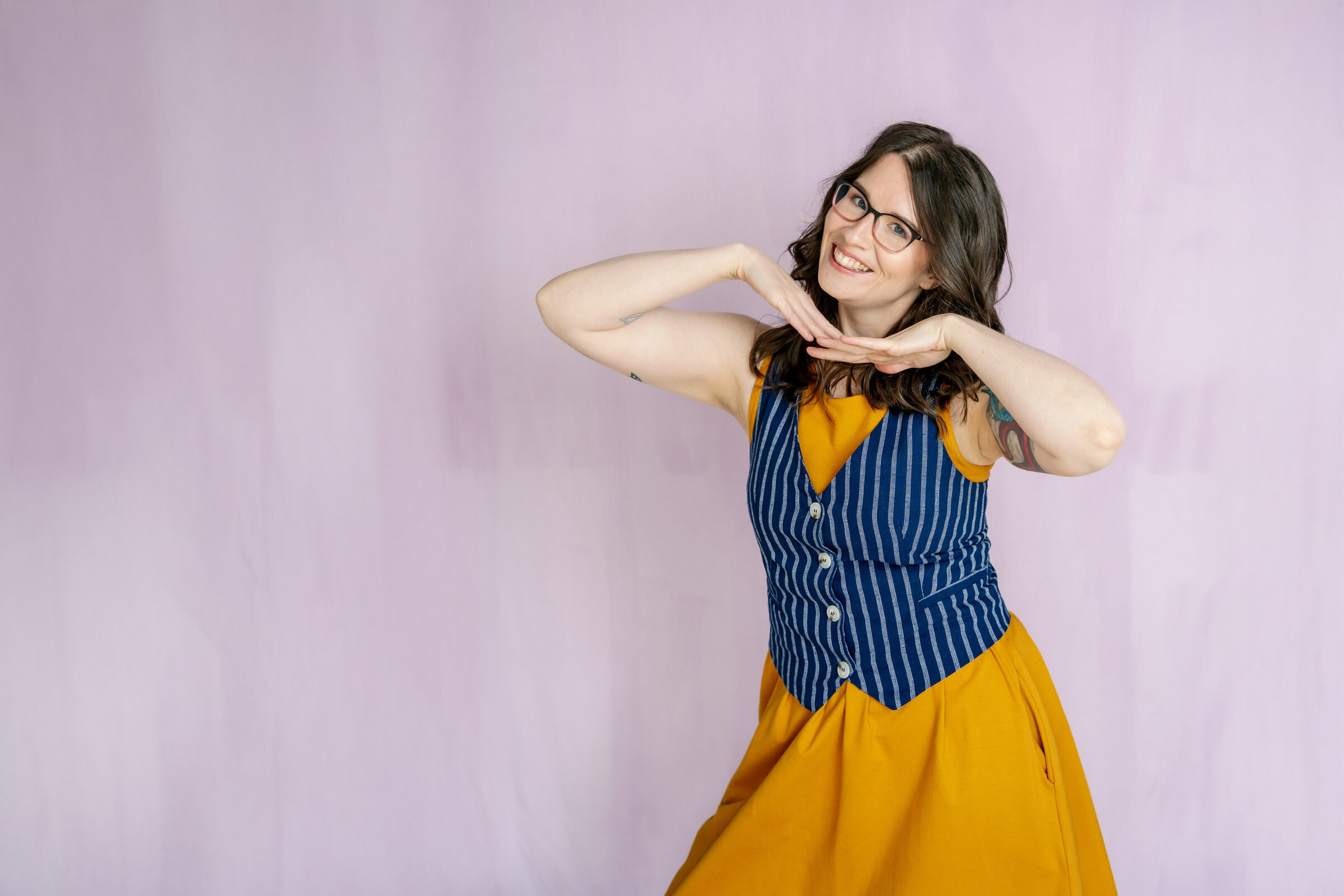 Brand Photographer Alicia LaPierre wearing a yellow shirt and blue cover happy dancing and smiling