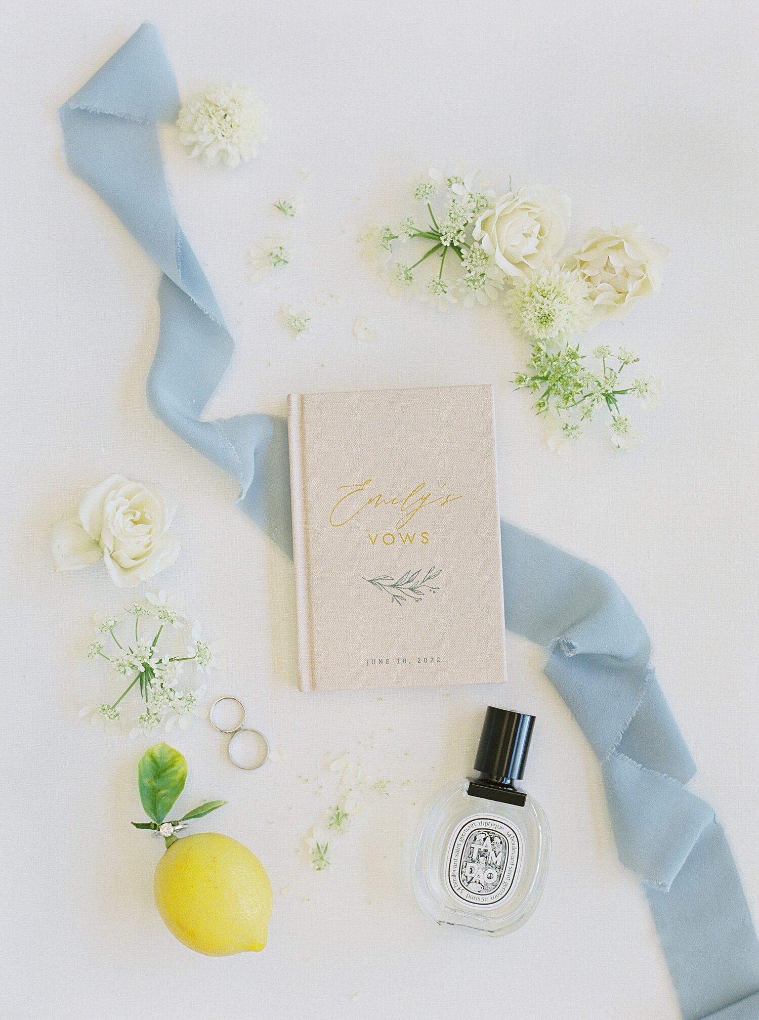 flat lay of vow book and light blue ribbon with lemon decor details