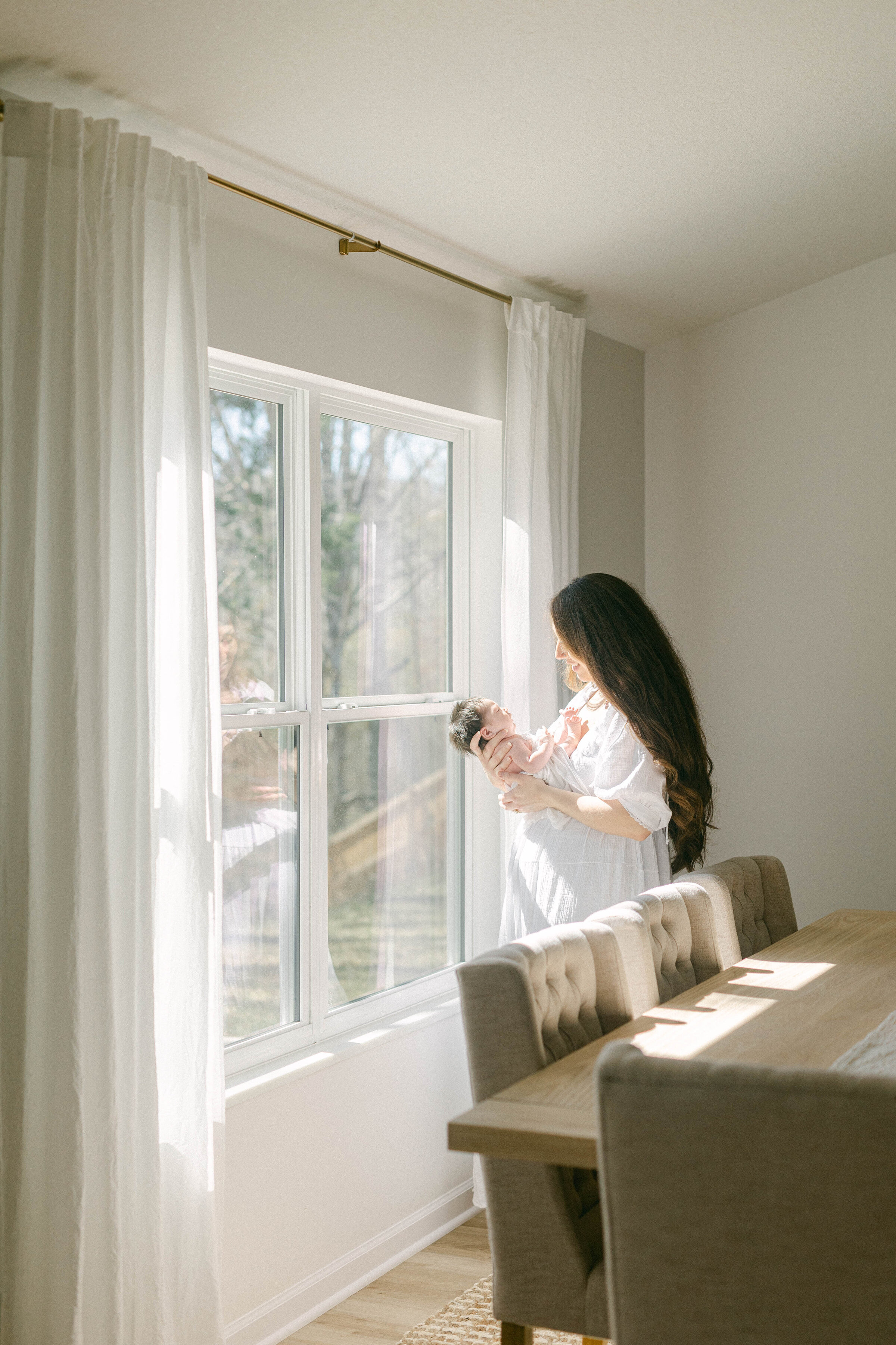 women holding baby in home with sunlight streaming in the windows  knoxville tennessee newborn photographer