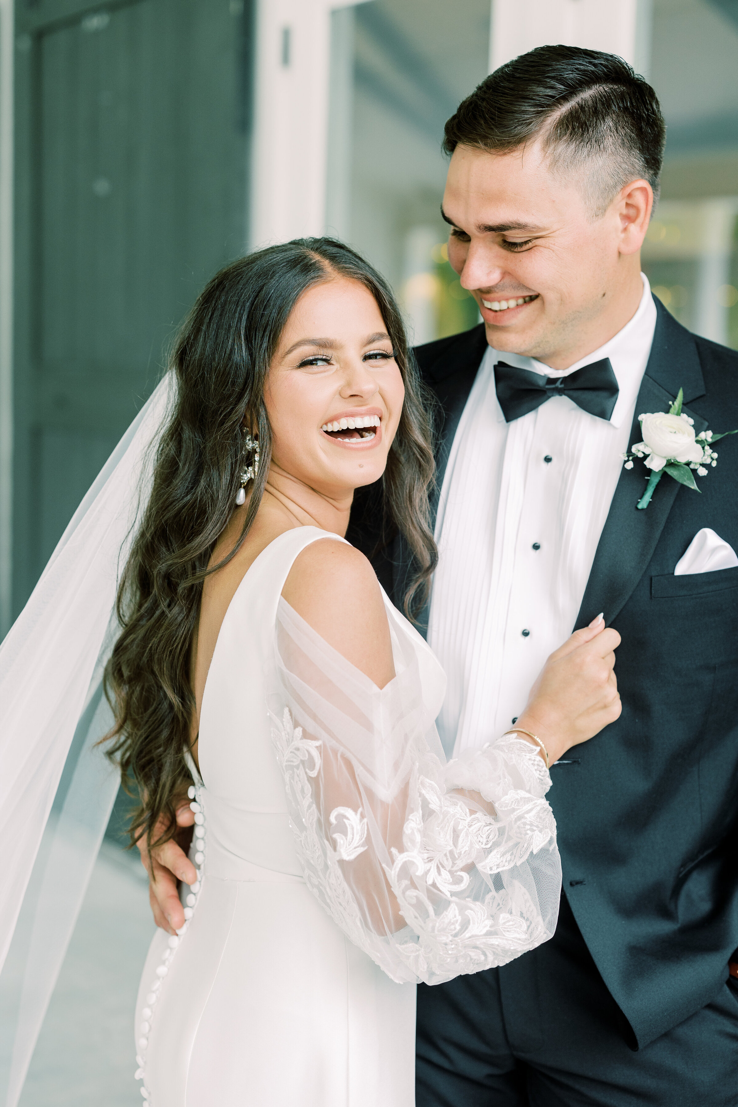 Bride and groom embracing, bride laughing