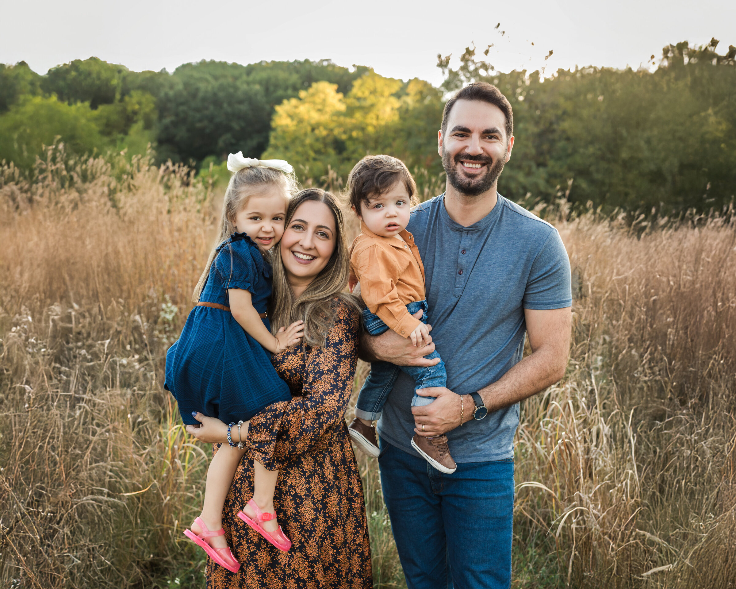 parents holding two children in field for family portraits cleveland family photographer