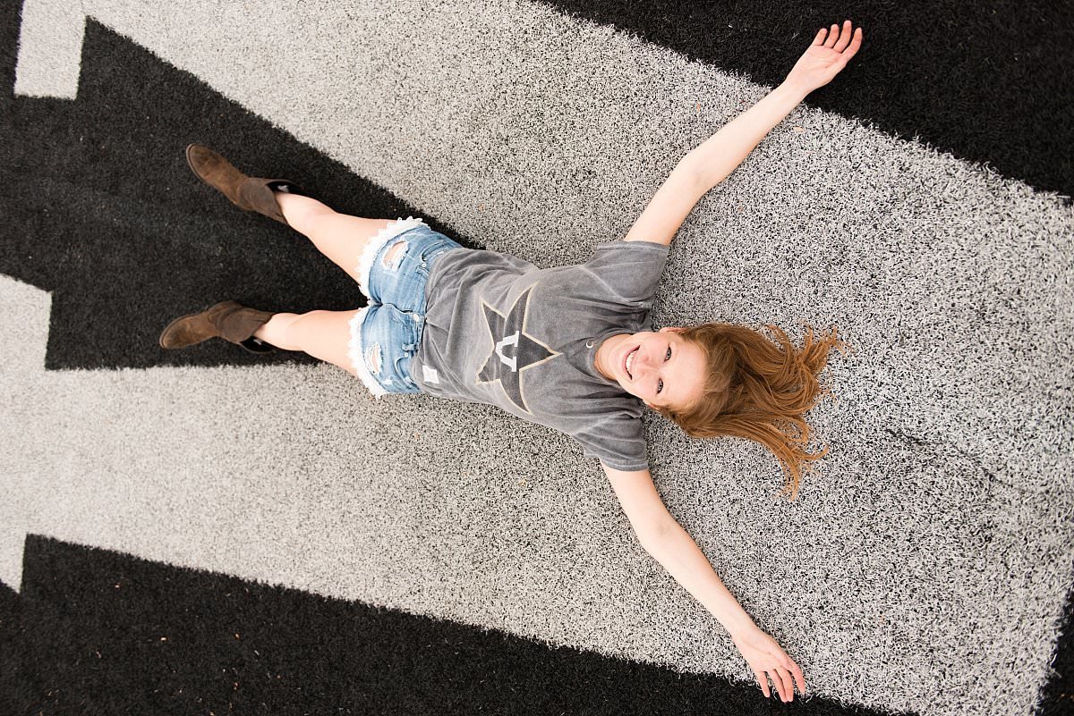 College senior wearing her Vanderbilt tshirt sprawled out on the V in the center of the Vandy football field