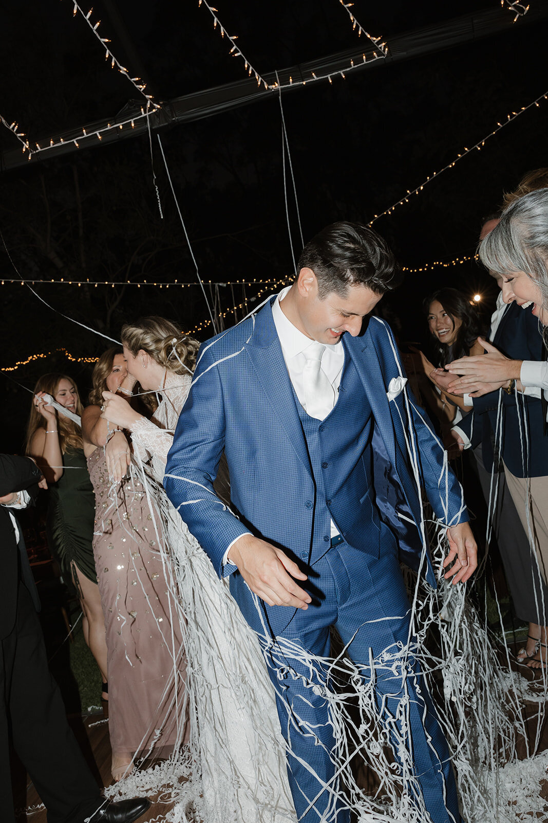 A bride and groom getting confetti string on them at the end of the evening. 