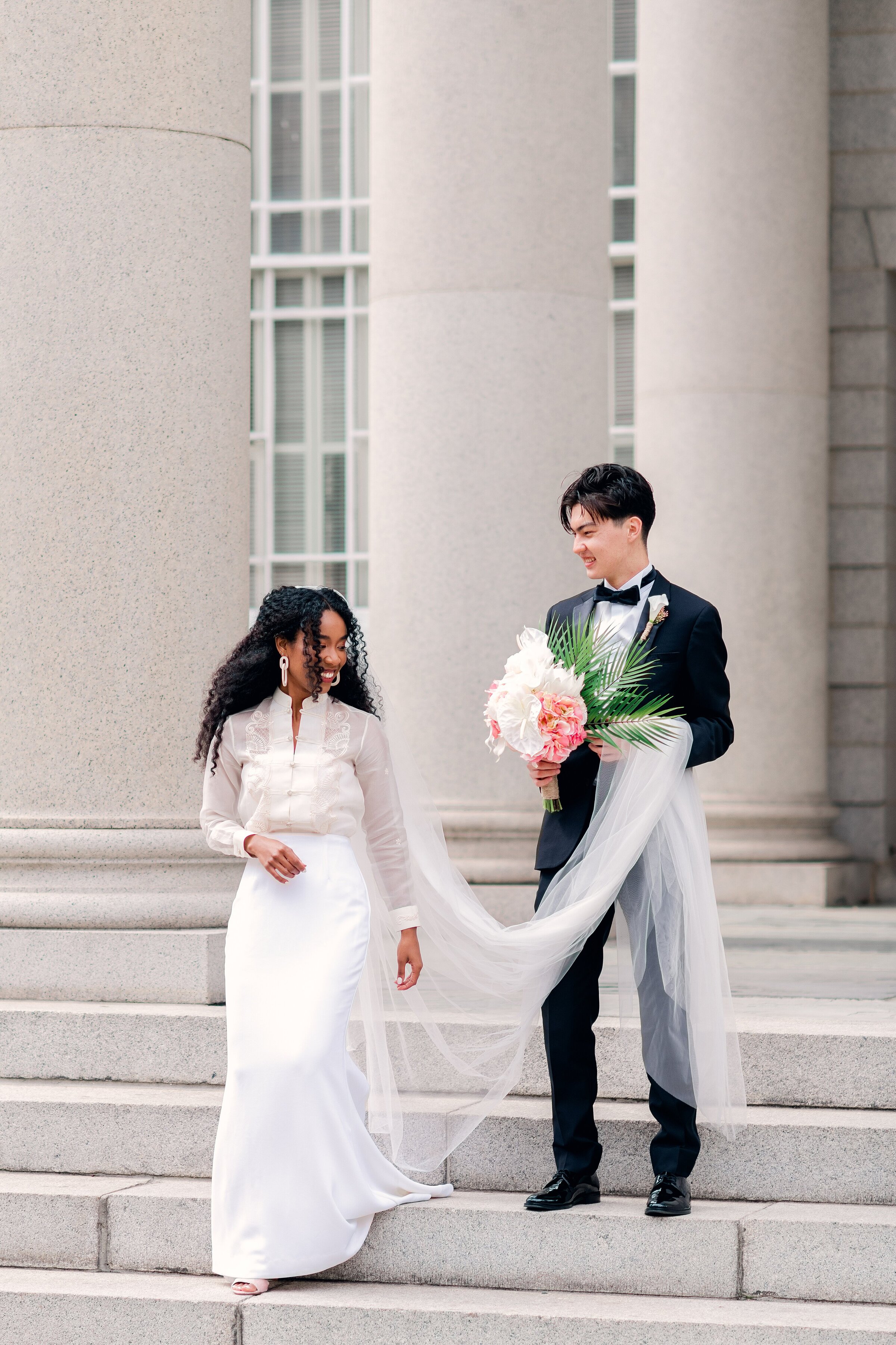 groom carries brides veil and flowers