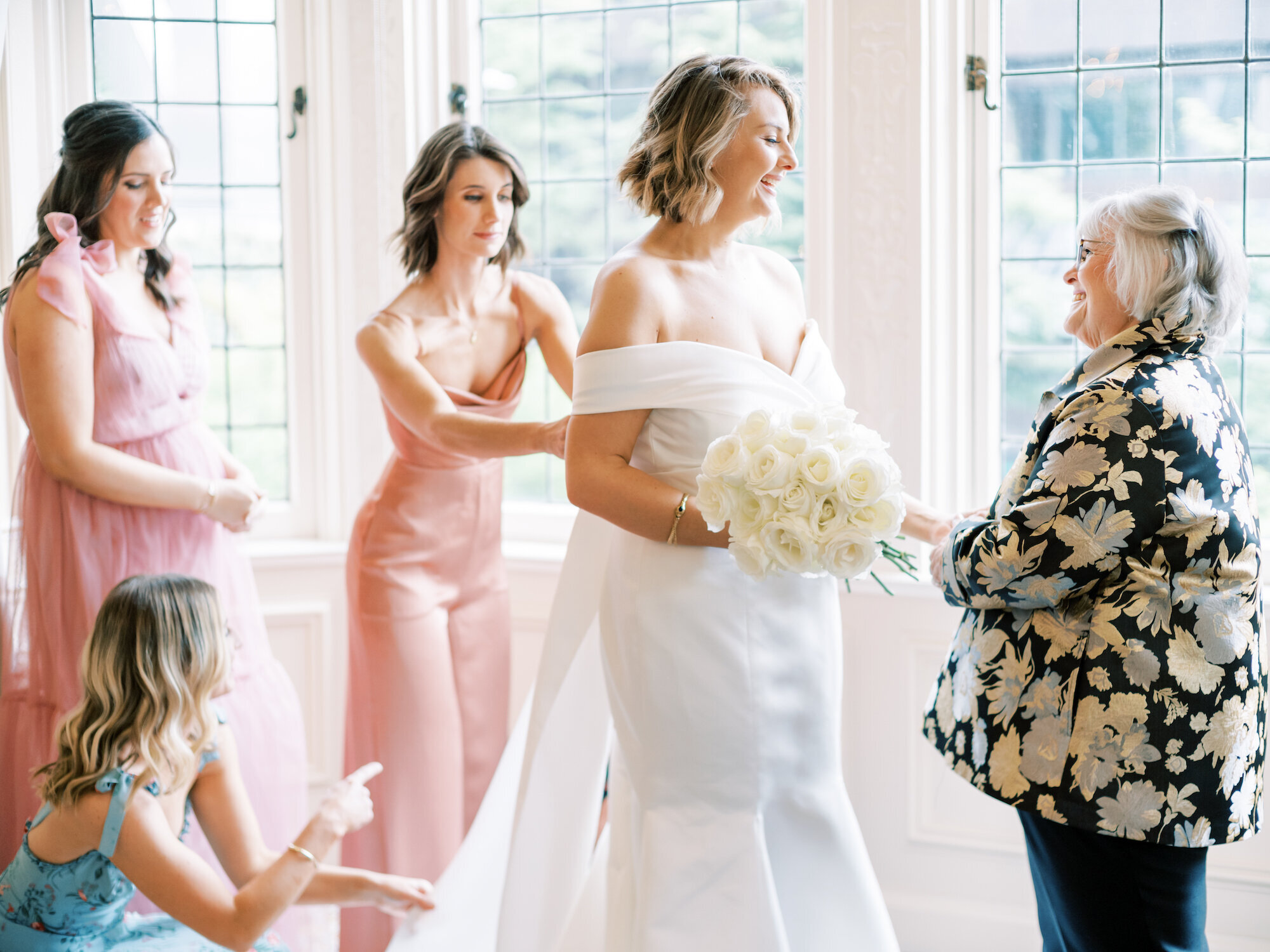 candid photo of bride smiling while getting dressed for her wedding