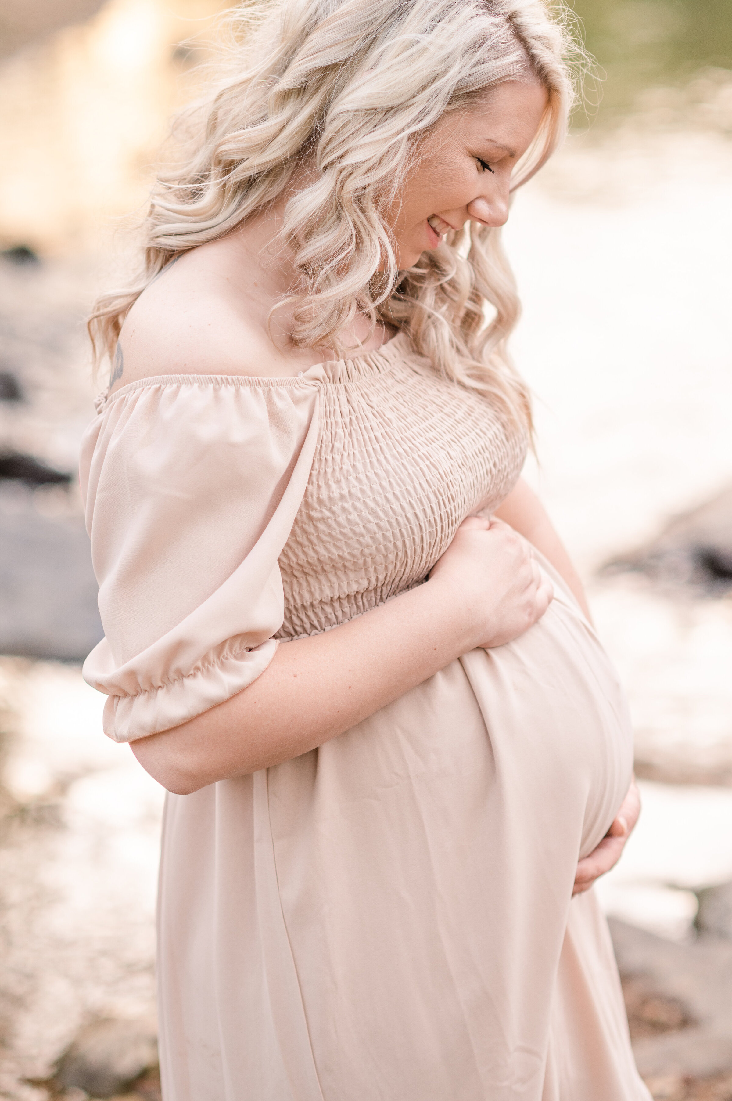maternity session with mother holding her belly smiling by a creek in harrisburg pa