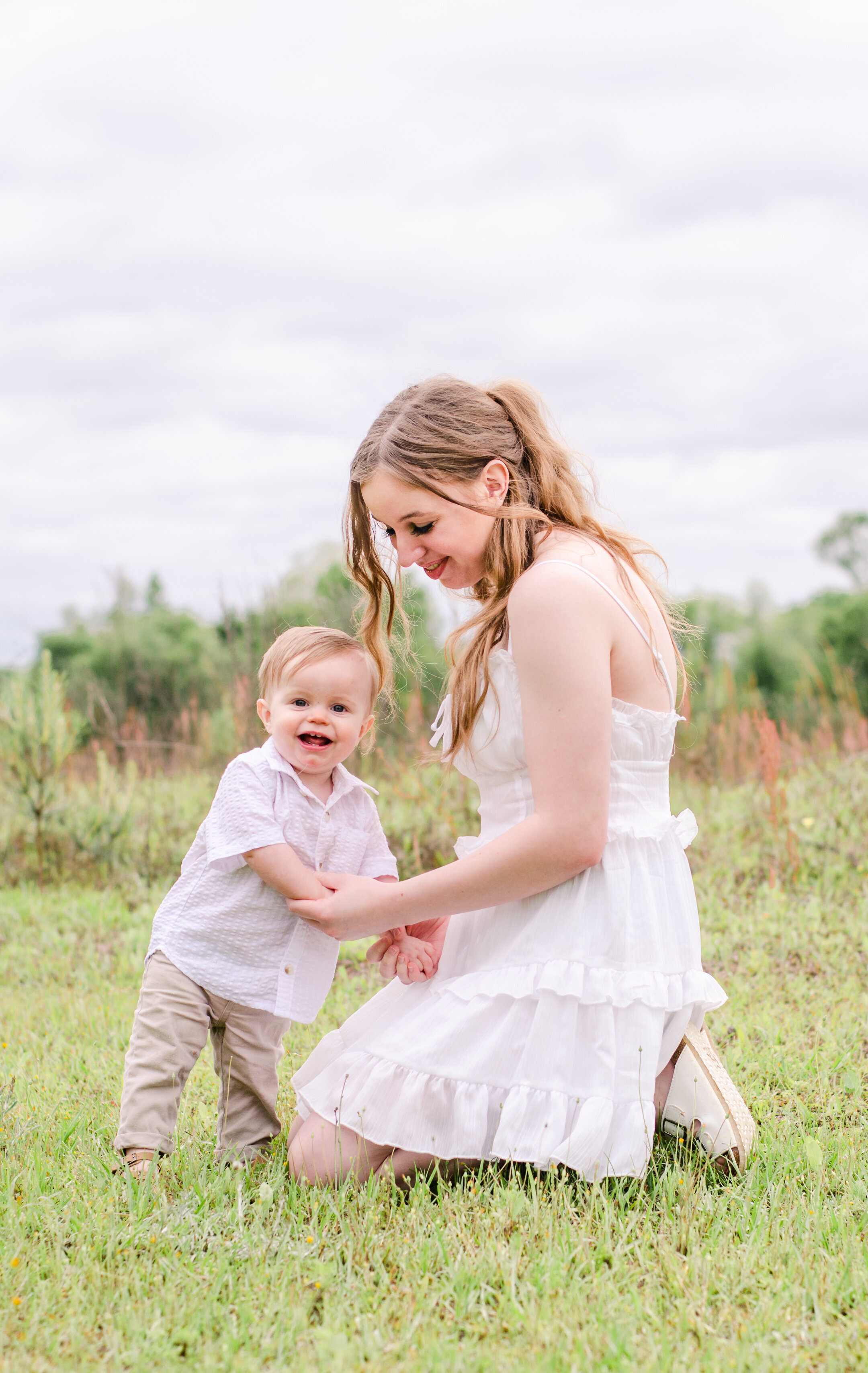 mom and baby play in a field