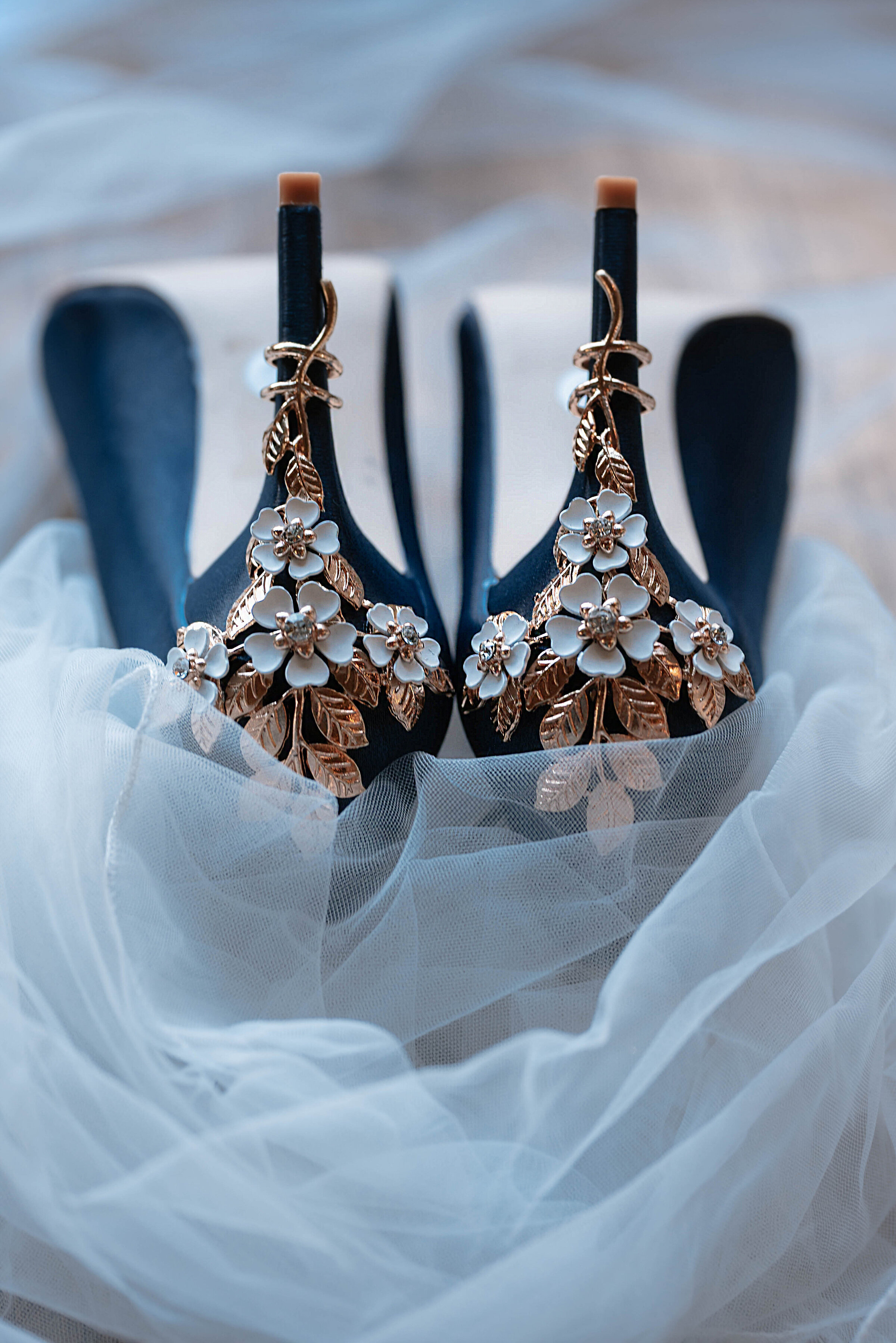 Deep royal blue high heels decorated with golden leaf and white floral embellishments