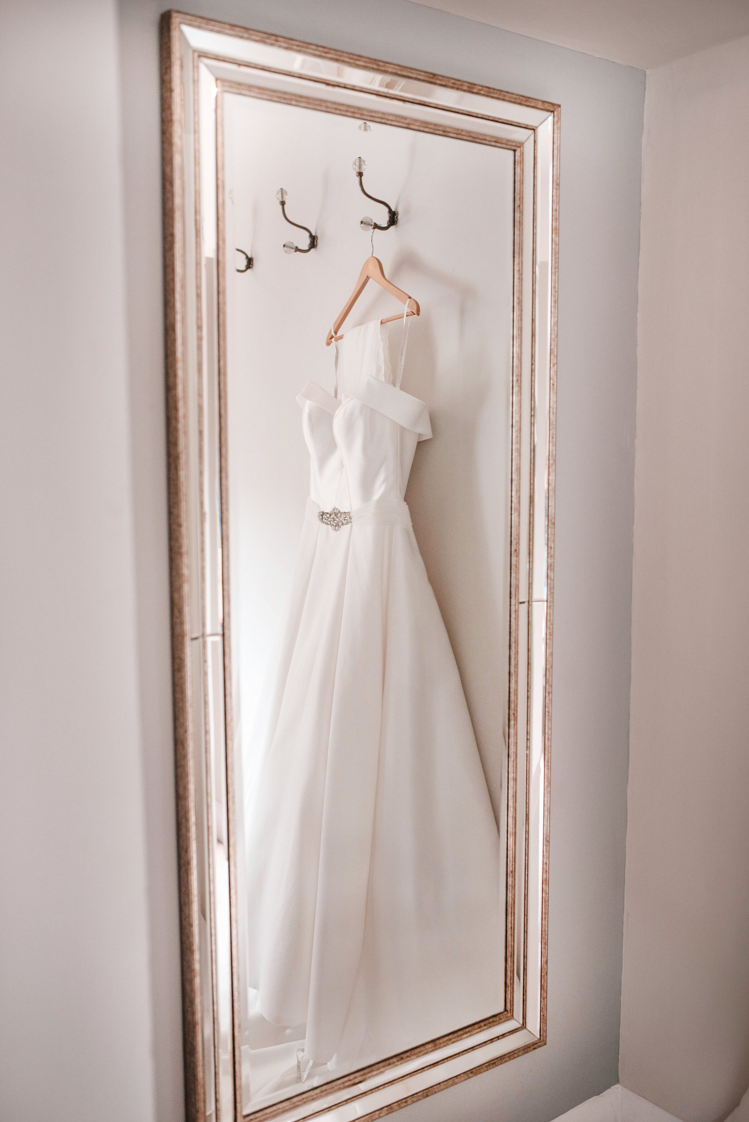 Mirrored reflection of a beautiful strapless wedding dress with veil and embellished belt