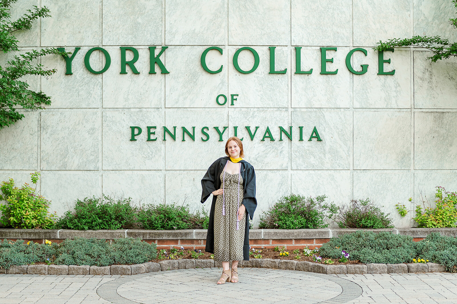Senior girl standing in front of the York College of Pennsylvania sign on campus