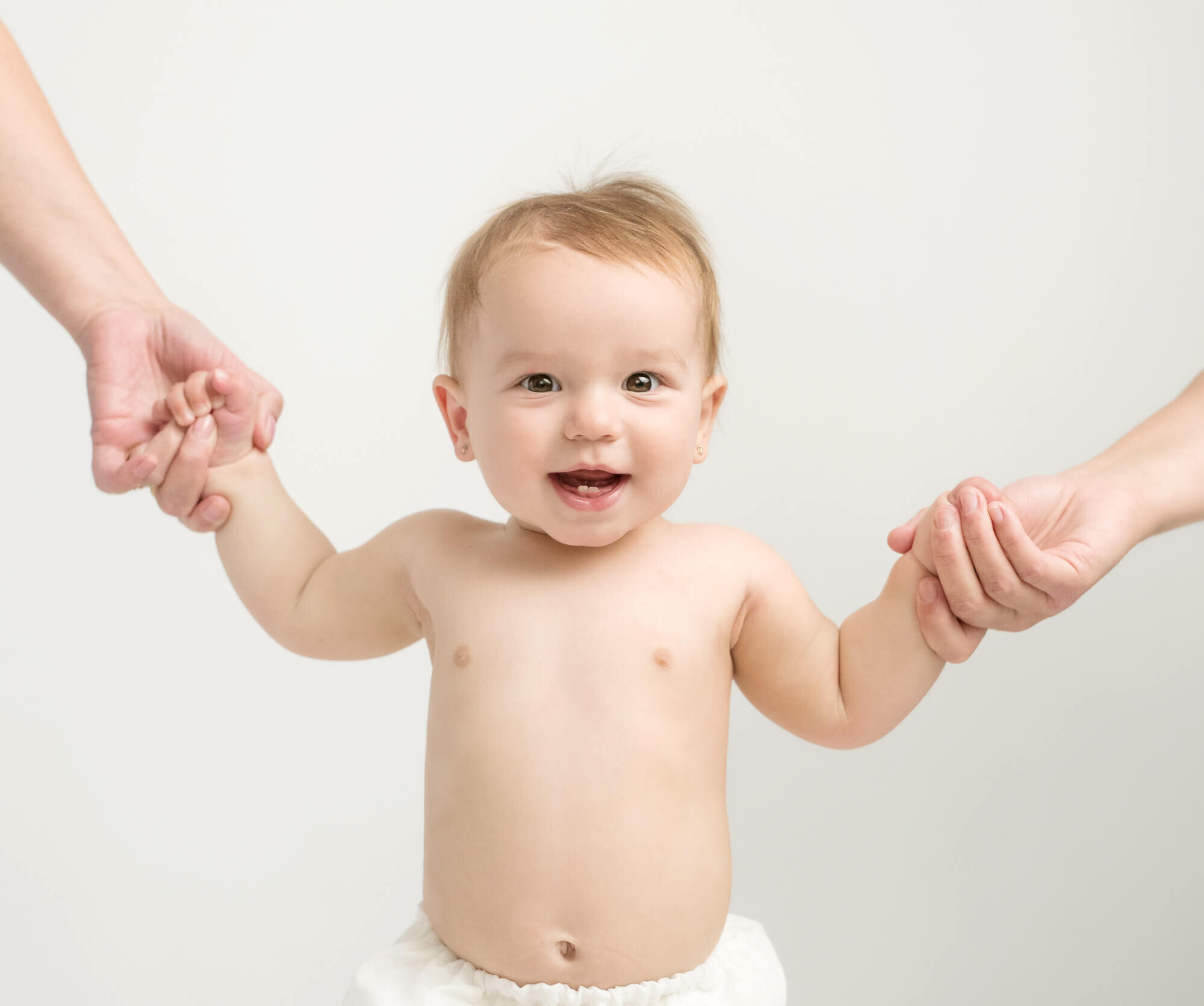 8 month baby standing holding parents hands
