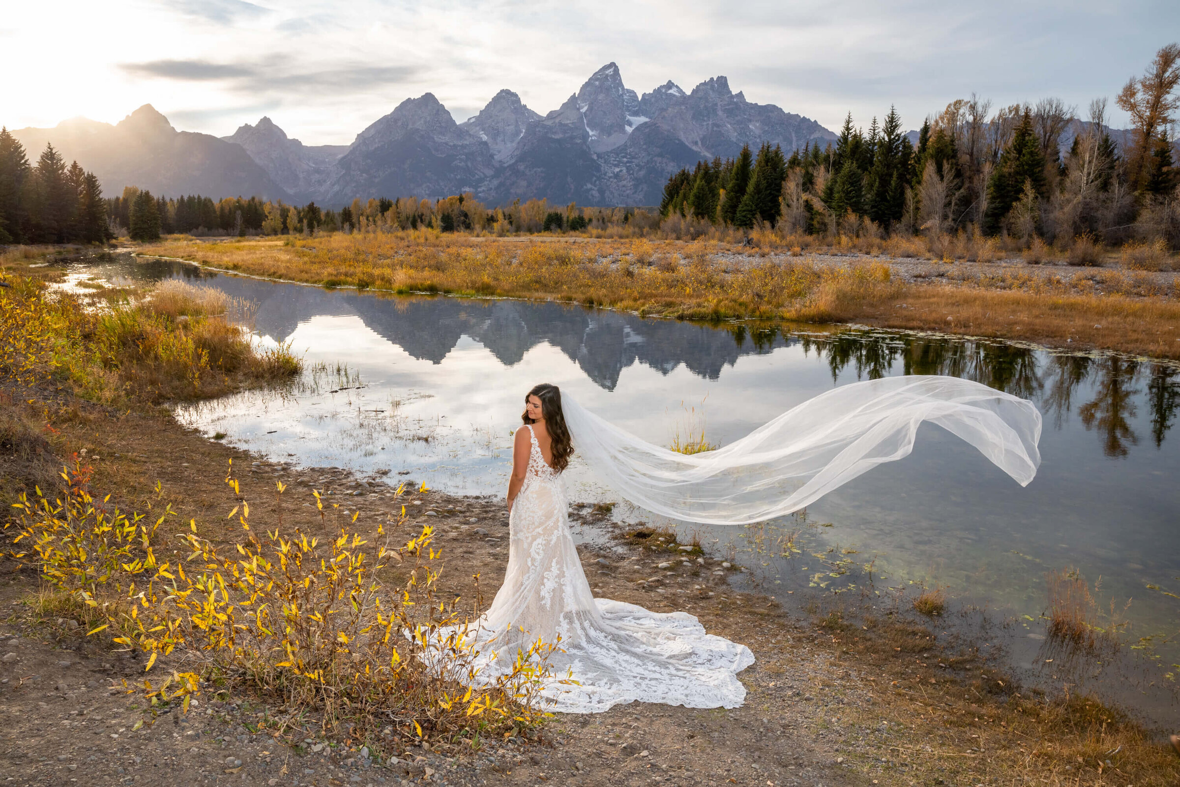 Bride's veil flows in the breeze at Schwabacher Landing, with the Grand Tetons reflecting in the still waters at sunset.