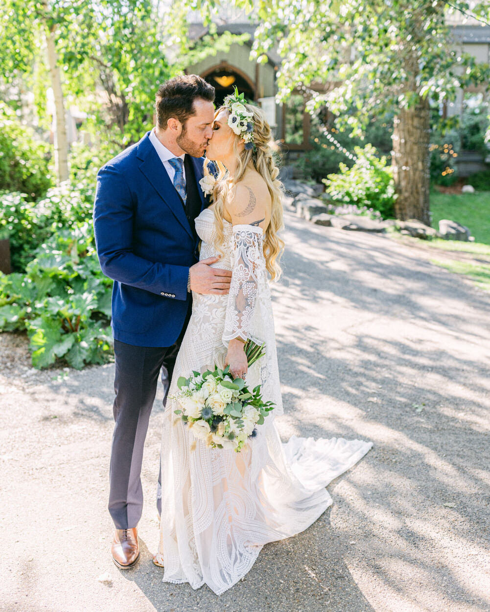 This romantic image captures a bride and groom sharing a kiss during their portrait session at River Café in downtown Calgary. The charming backdrop of the café, nestled in the heart of the city, adds an intimate and picturesque setting to their loving moment.
