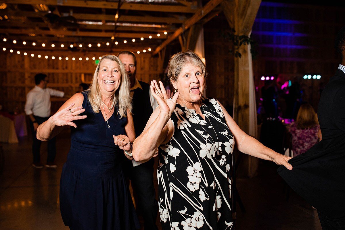 Wedding guests form a train on the dance floor, waving at camera as they pass by