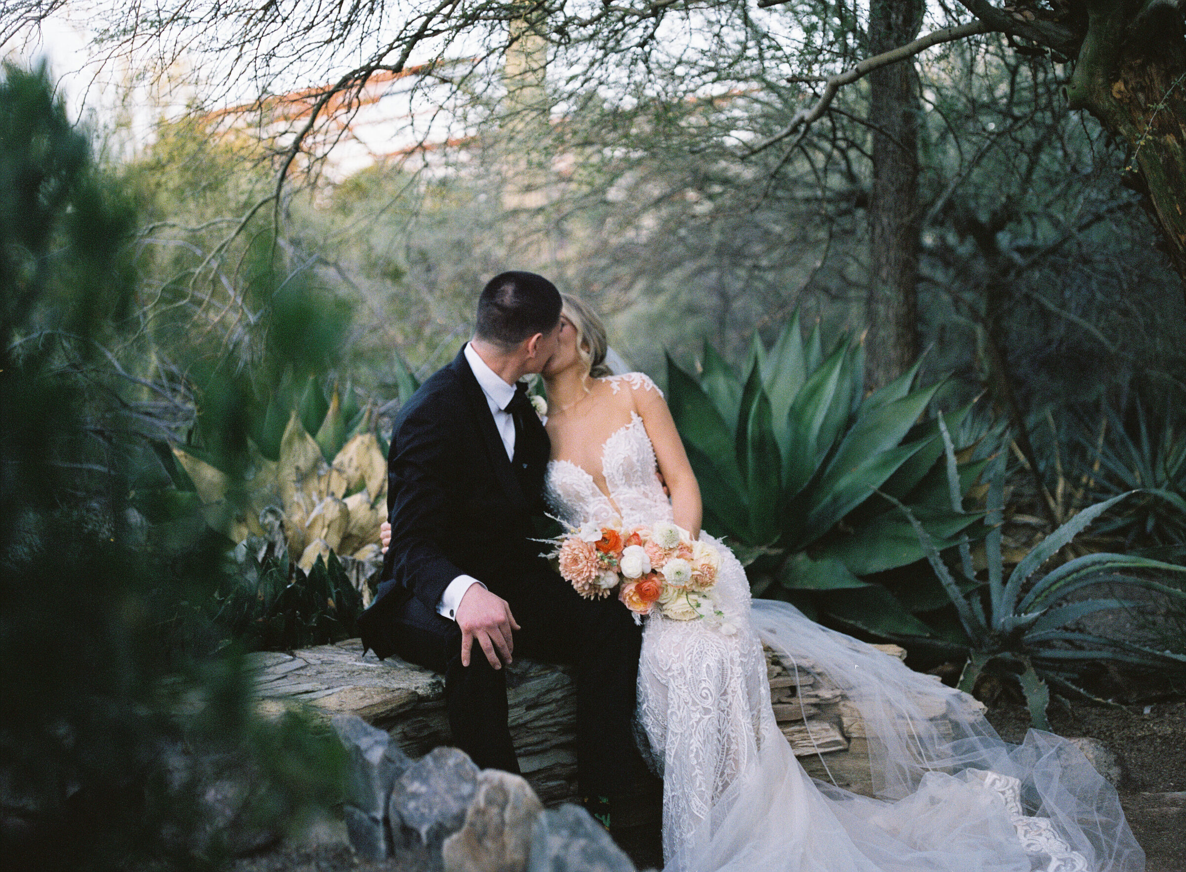 bride and groom kissing on rock