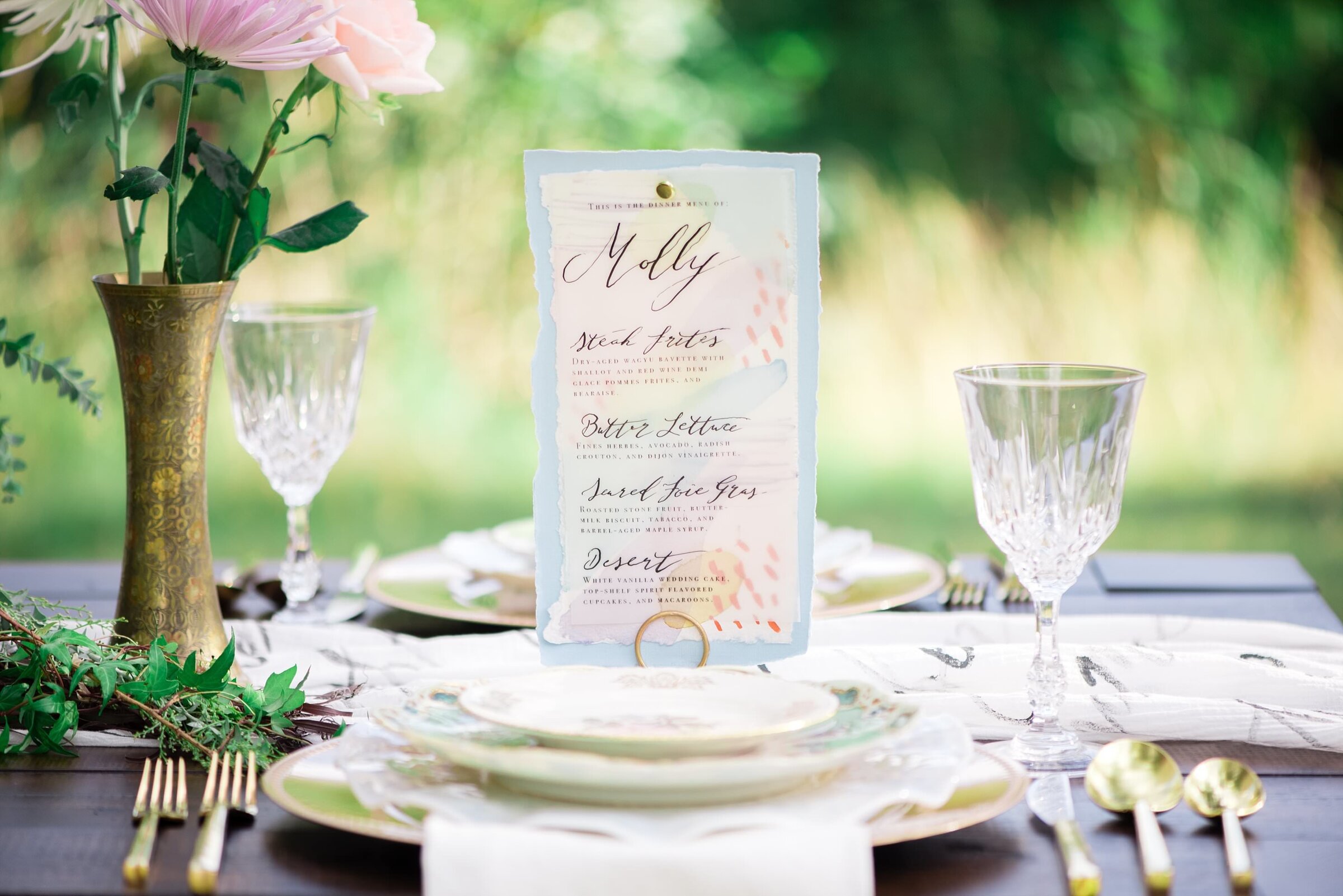 Menu cards with watercolor and hand calligraphy standing upright on vintage china, soft blue, pinks and gold design details