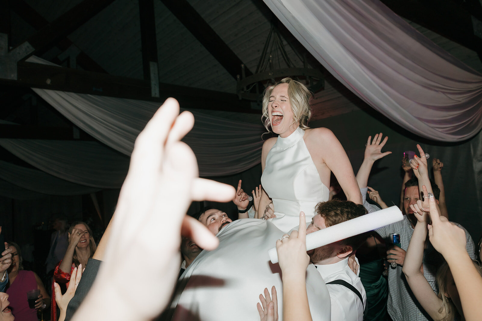 A bride being lifted up during dancing at her wedding reception.