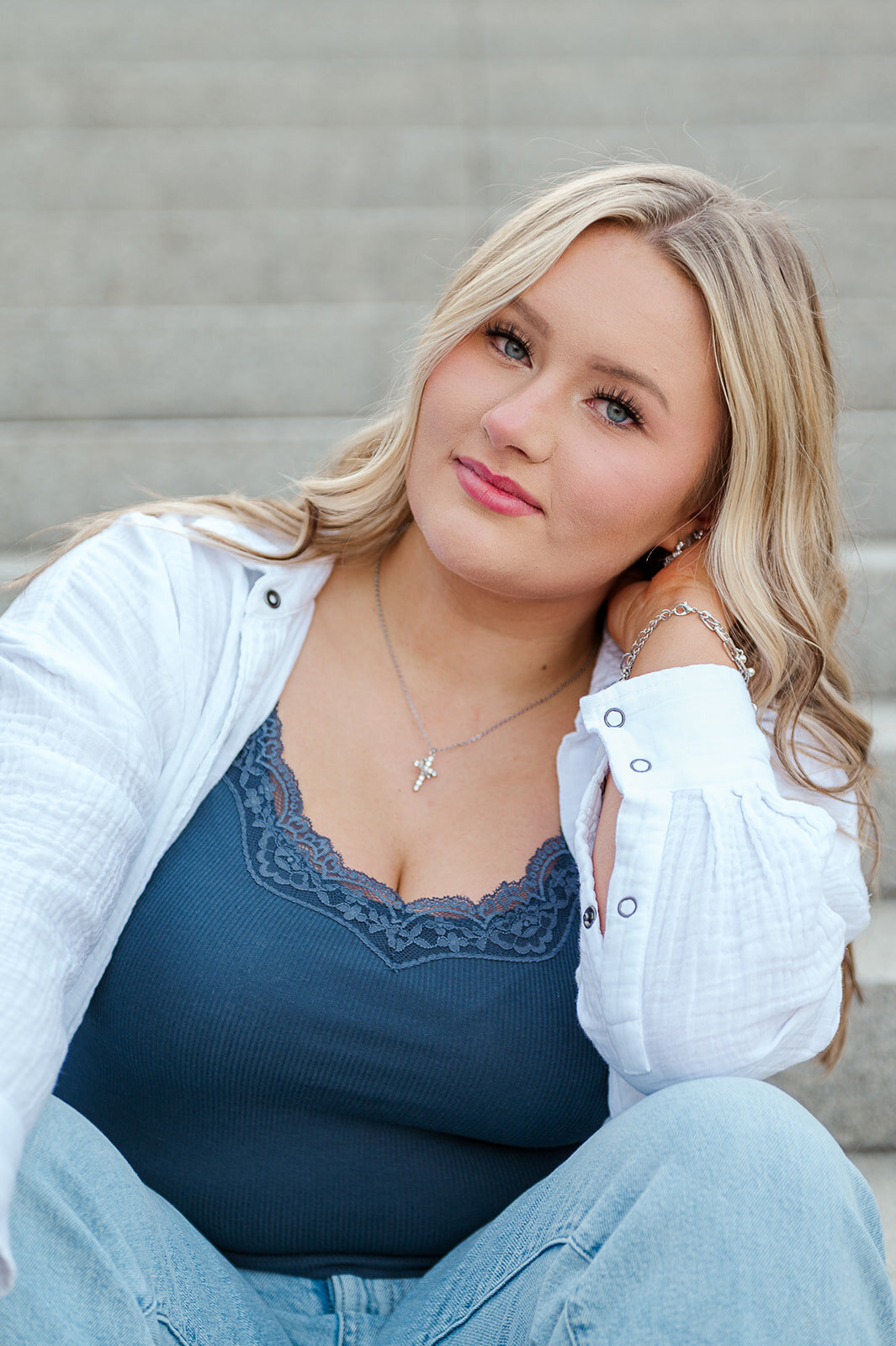Senior girl sitting on city stairs wearing a blue tank and white sweater in Harrisburg, PA