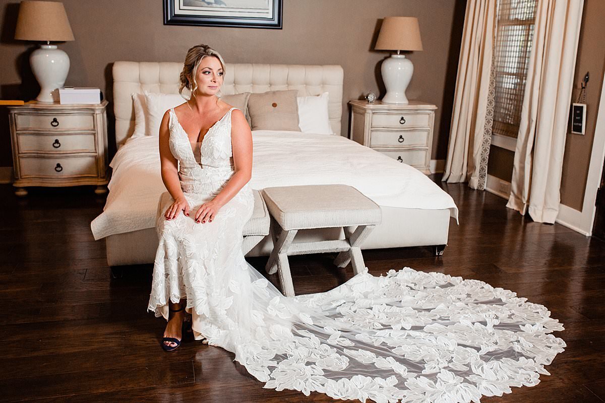 Bride sitting inside suite with lace train spread out to the side