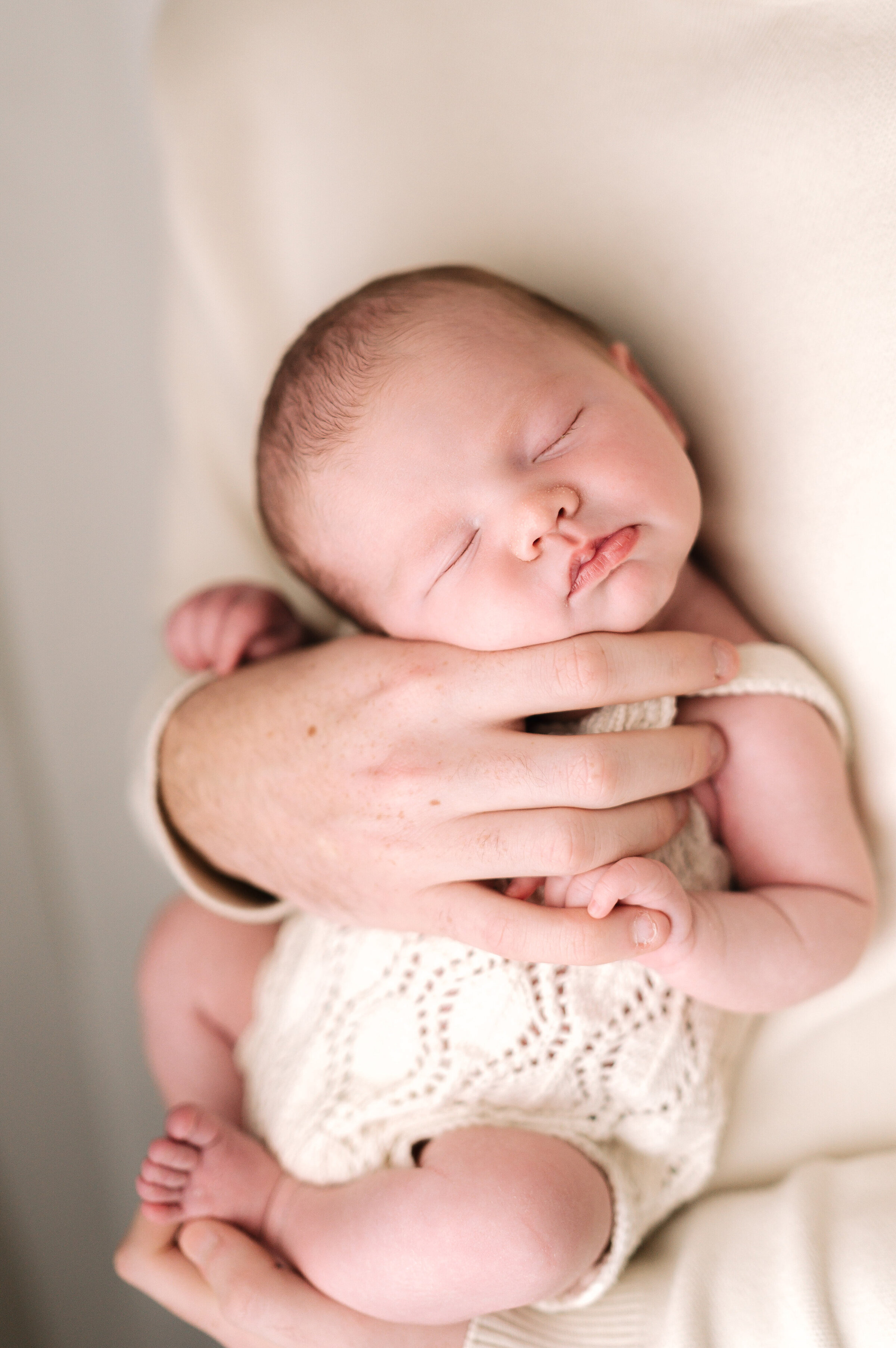 Dad holding his newborn baby with his hands holding their chin up at Billingshurst newborn photoshoot