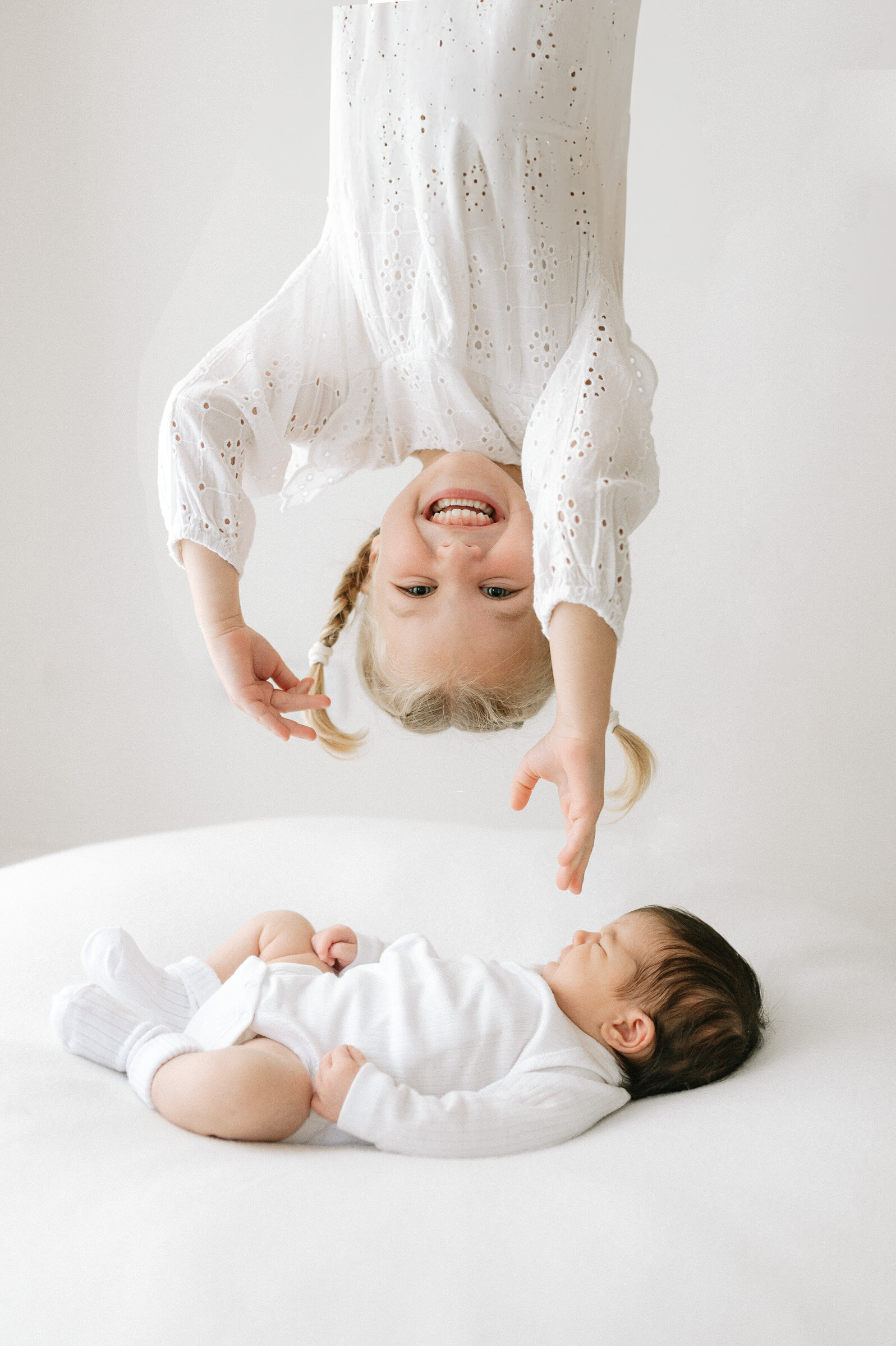 Big sister leaning over her baby sister in York studio