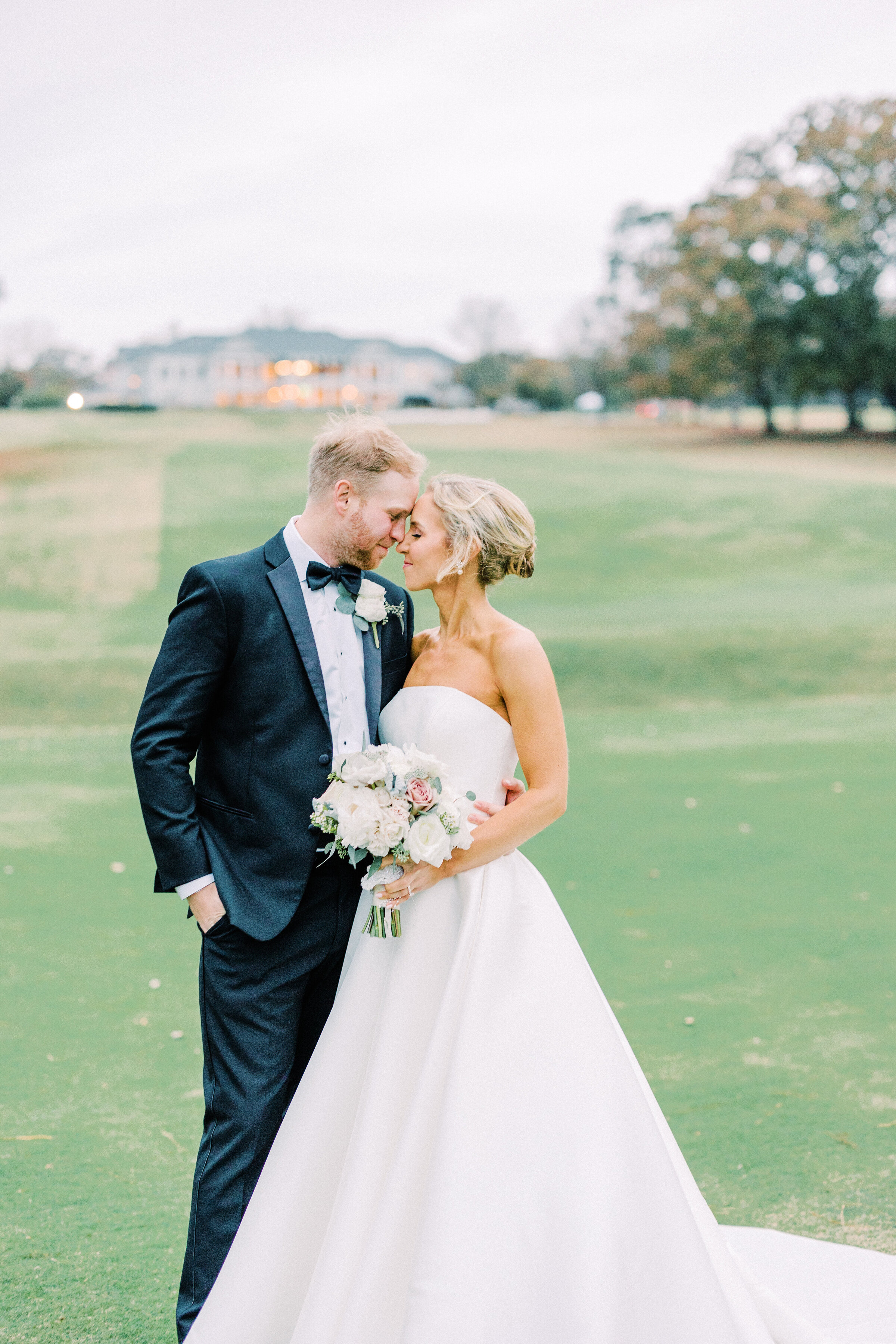 Bride and groom with foreheads pressed together standing outside