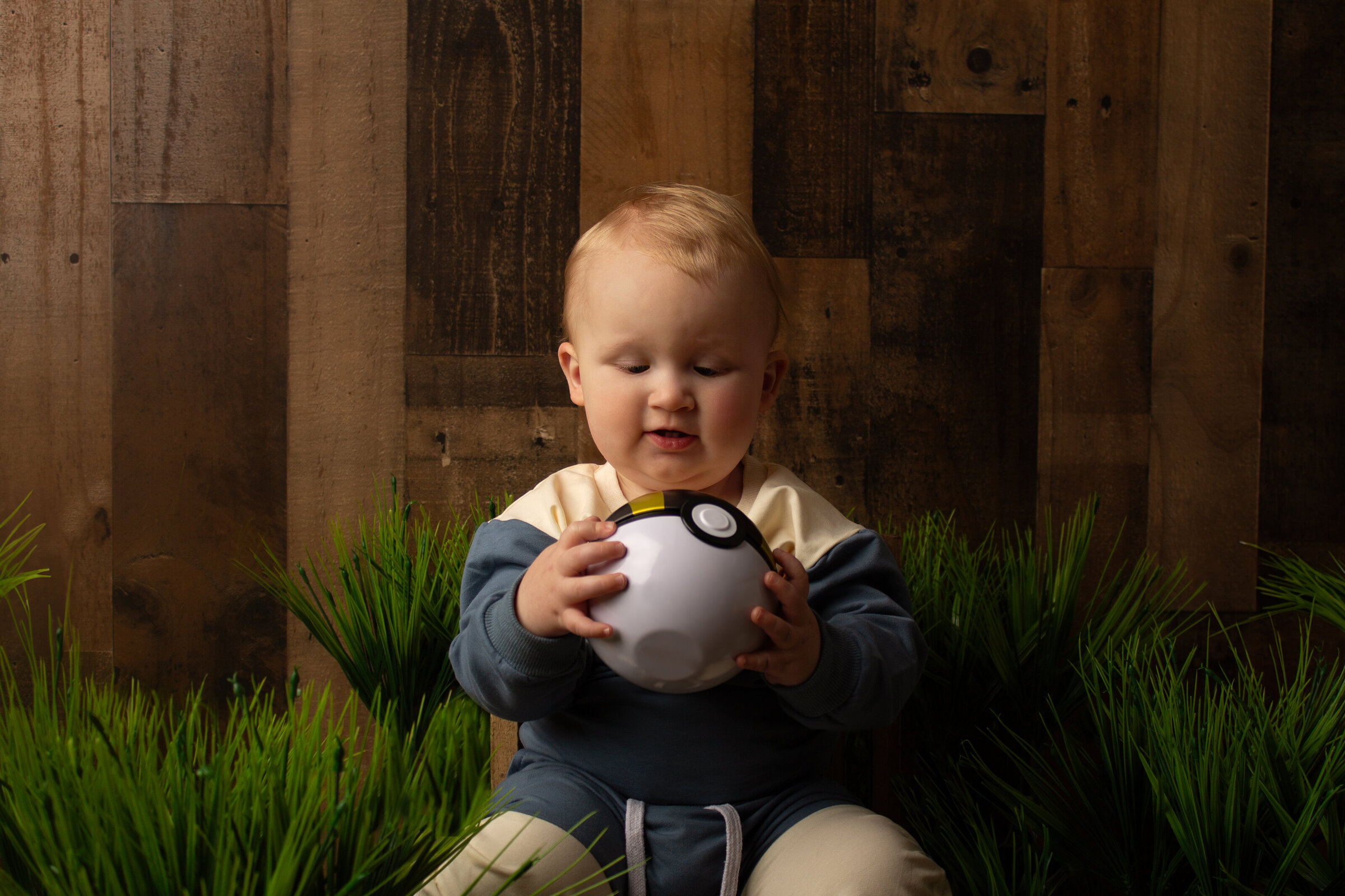 Little boy looking down at a ball in his hands.
