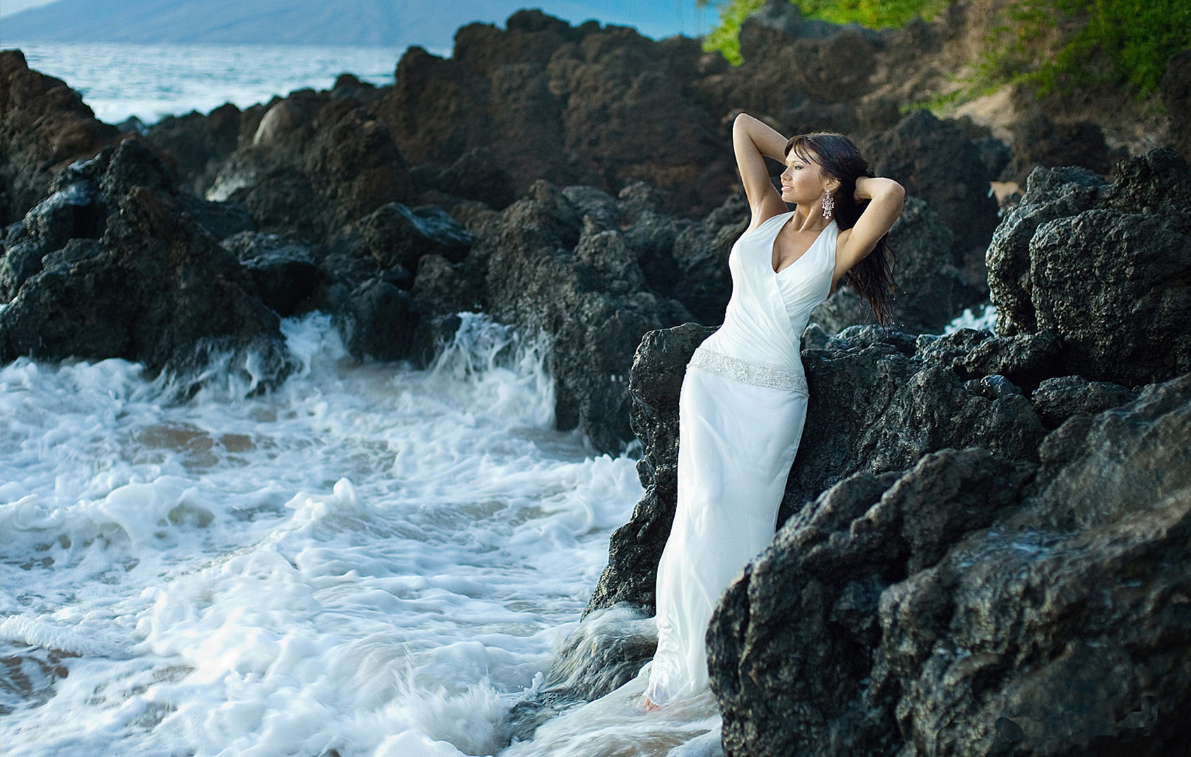 bride on the rocks has fun with the waves