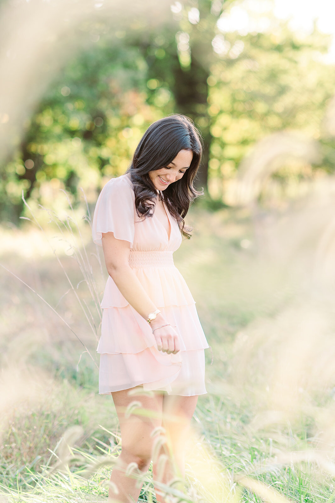 senior girl in pink dress walking through tall grass by hershy pa photographer