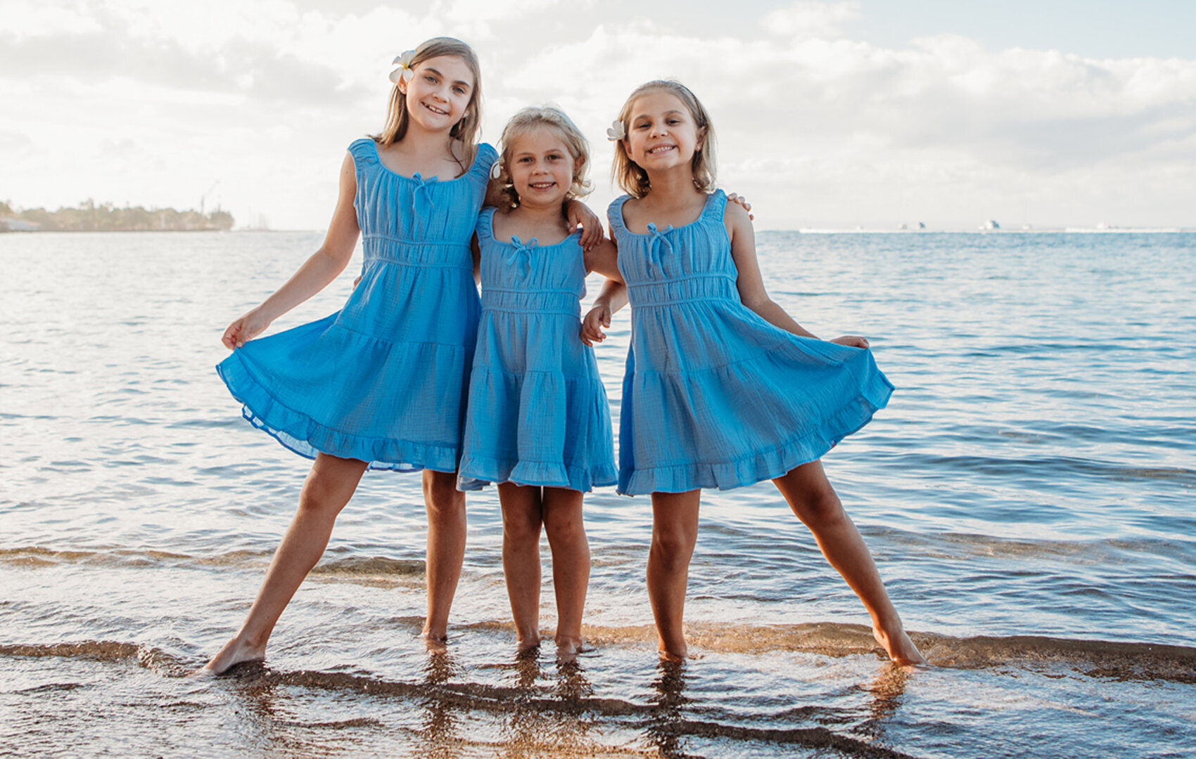 All in blue and happy for you, three sisters pose in the water for their Hawaii photography session.