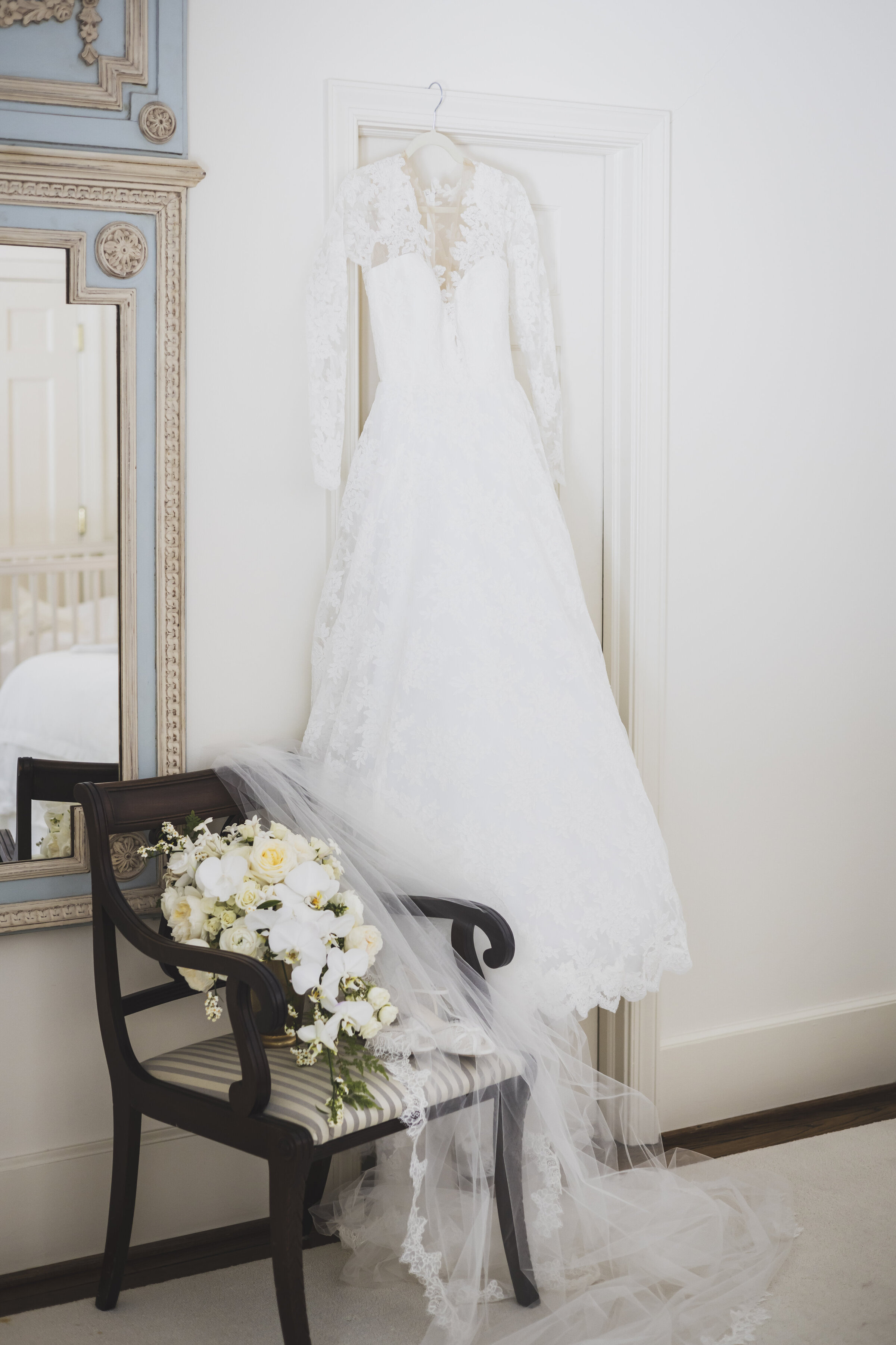 Wedding dress  hanging over chair with bouquet.