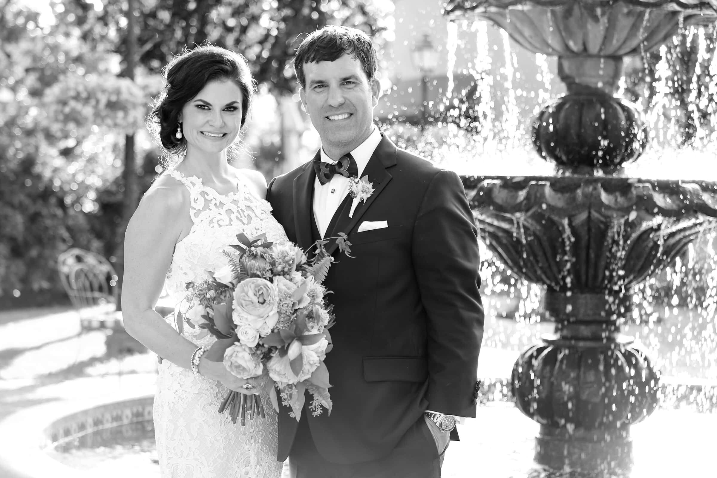 Black and white portrait of newly married couple in front of a fountain at italian  wedding venue.