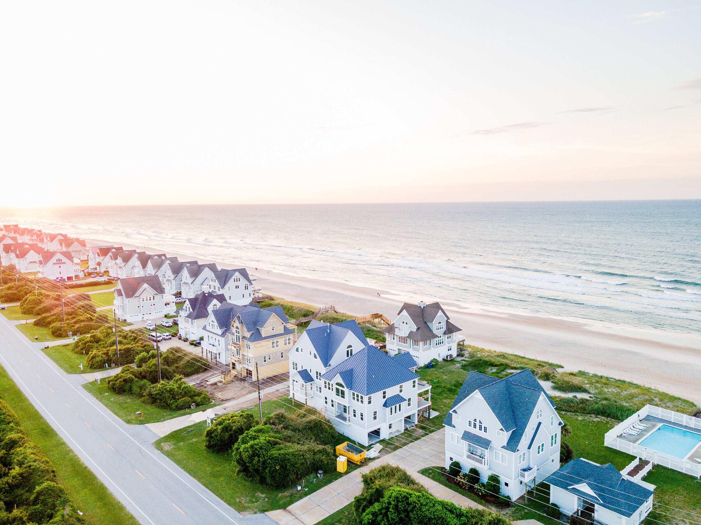 A breathtaking aerial shot showcasing custom high-end homes along the long shore. The image captures the elegance and luxury of these waterfront properties, highlighting their prime location and stunning architecture.