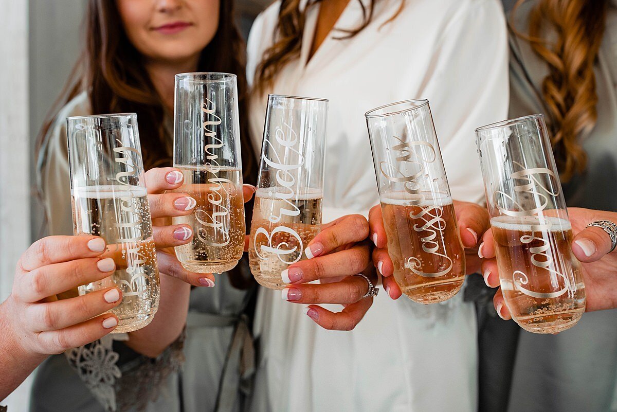 Custom calligraphy on modern wine spritzer glasses, bridesmaids holding them with champagne