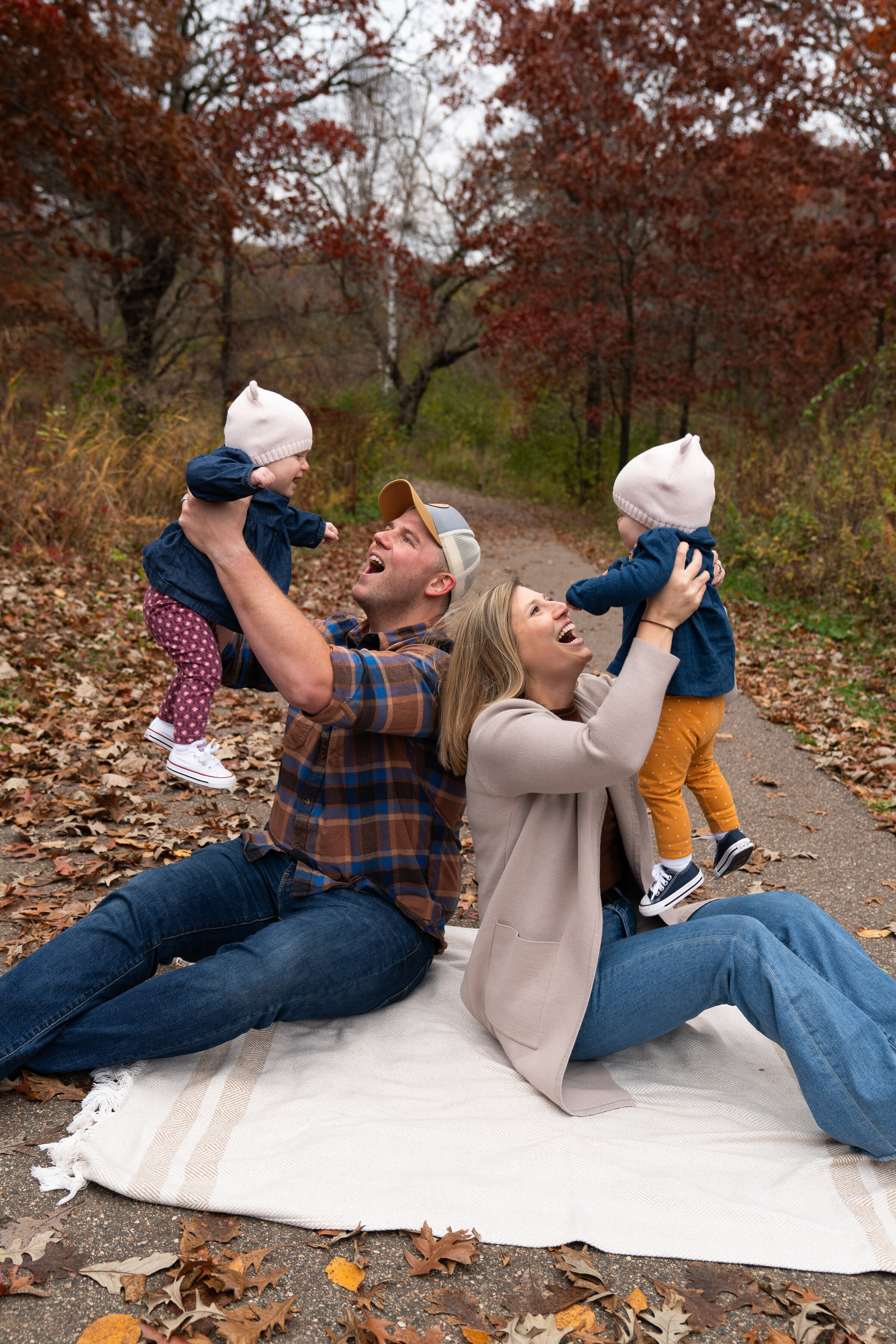 A mom and dad lift their twin daughters in the air during their family pictures.