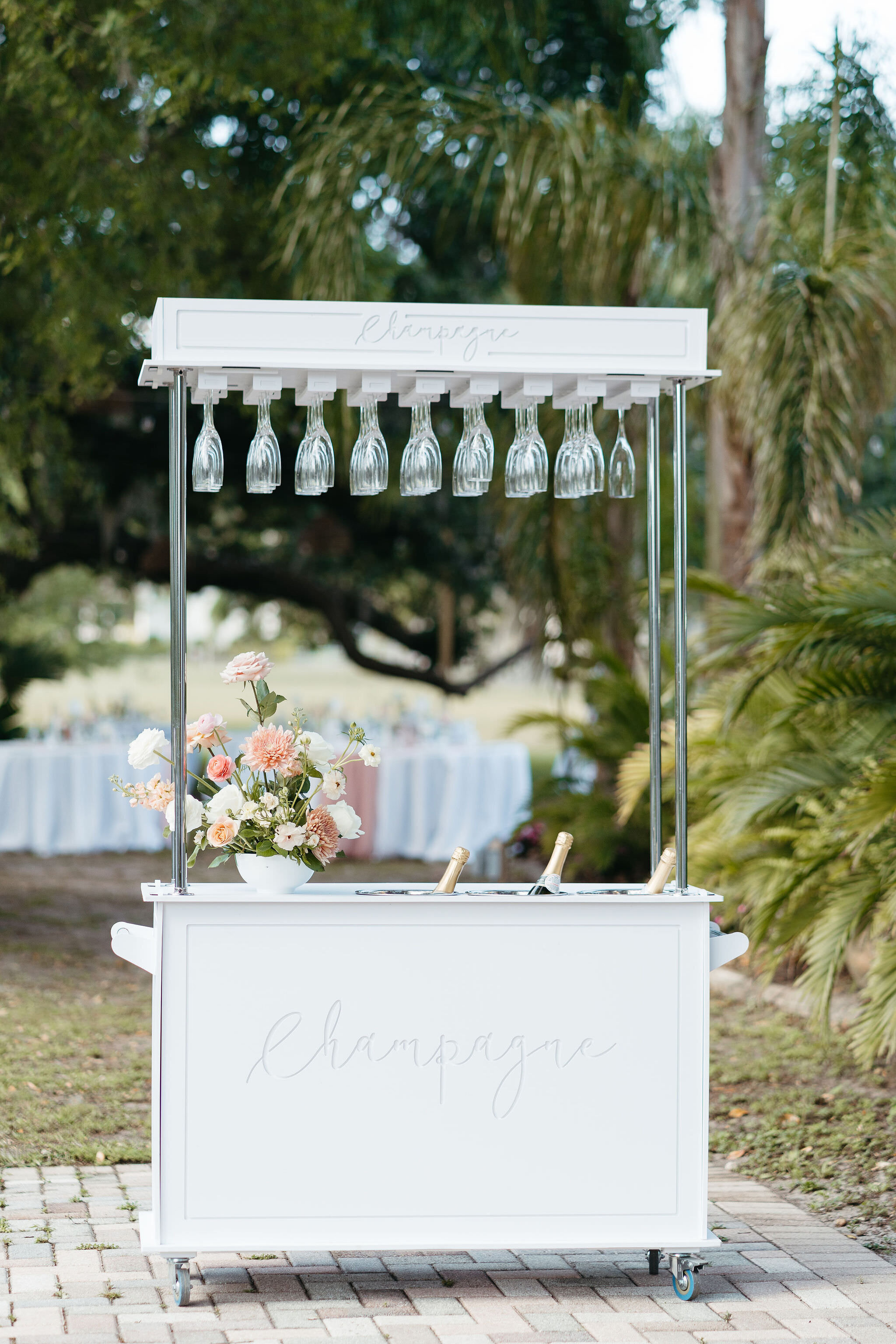 Elegant white champagne cart with hanging glassware and fresh flowers at Uliana Estate wedding in Lakeland, Florida

