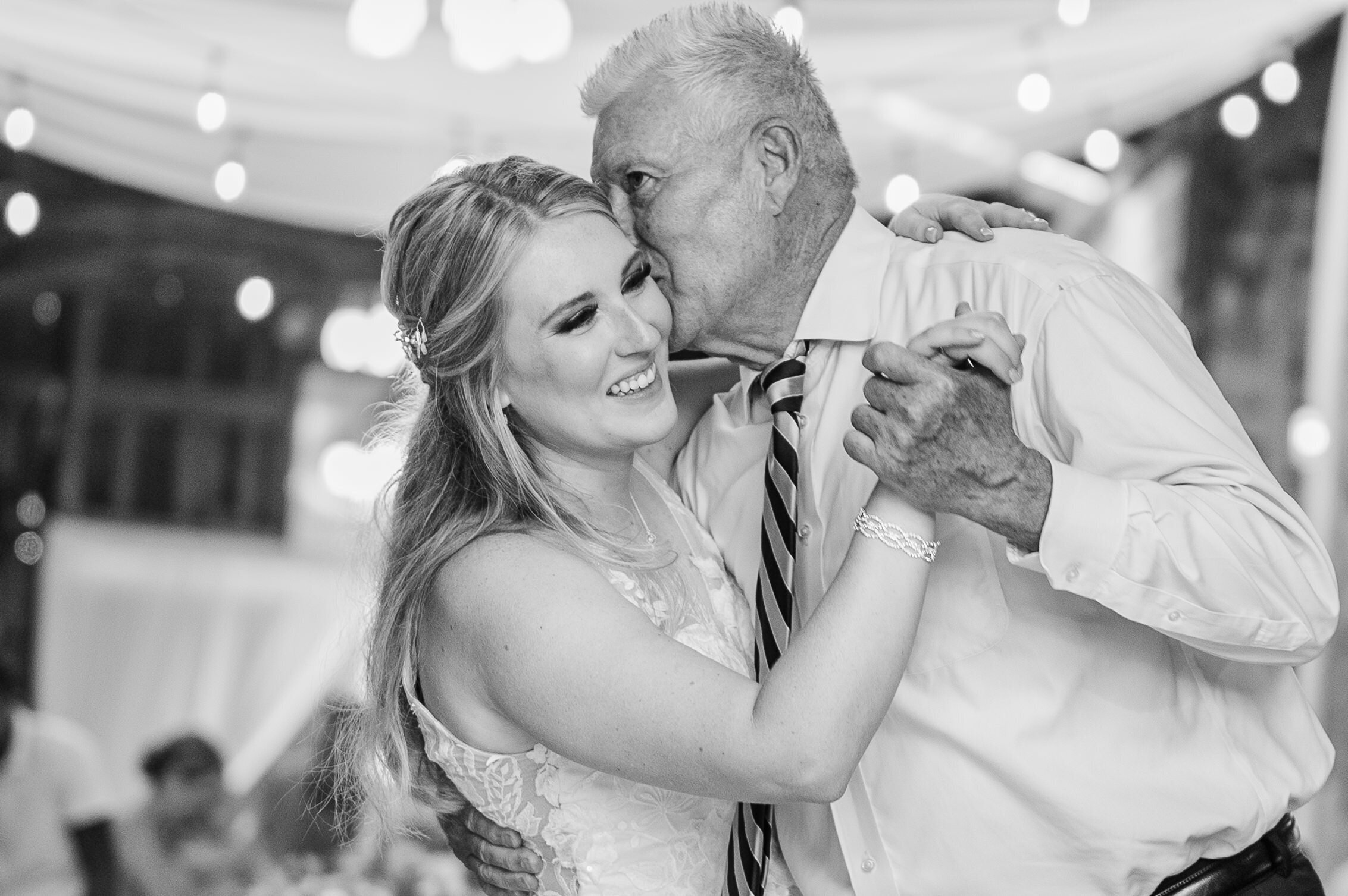 A father kisses his daughters forehead during their first dance at Land O'Goshen Farms