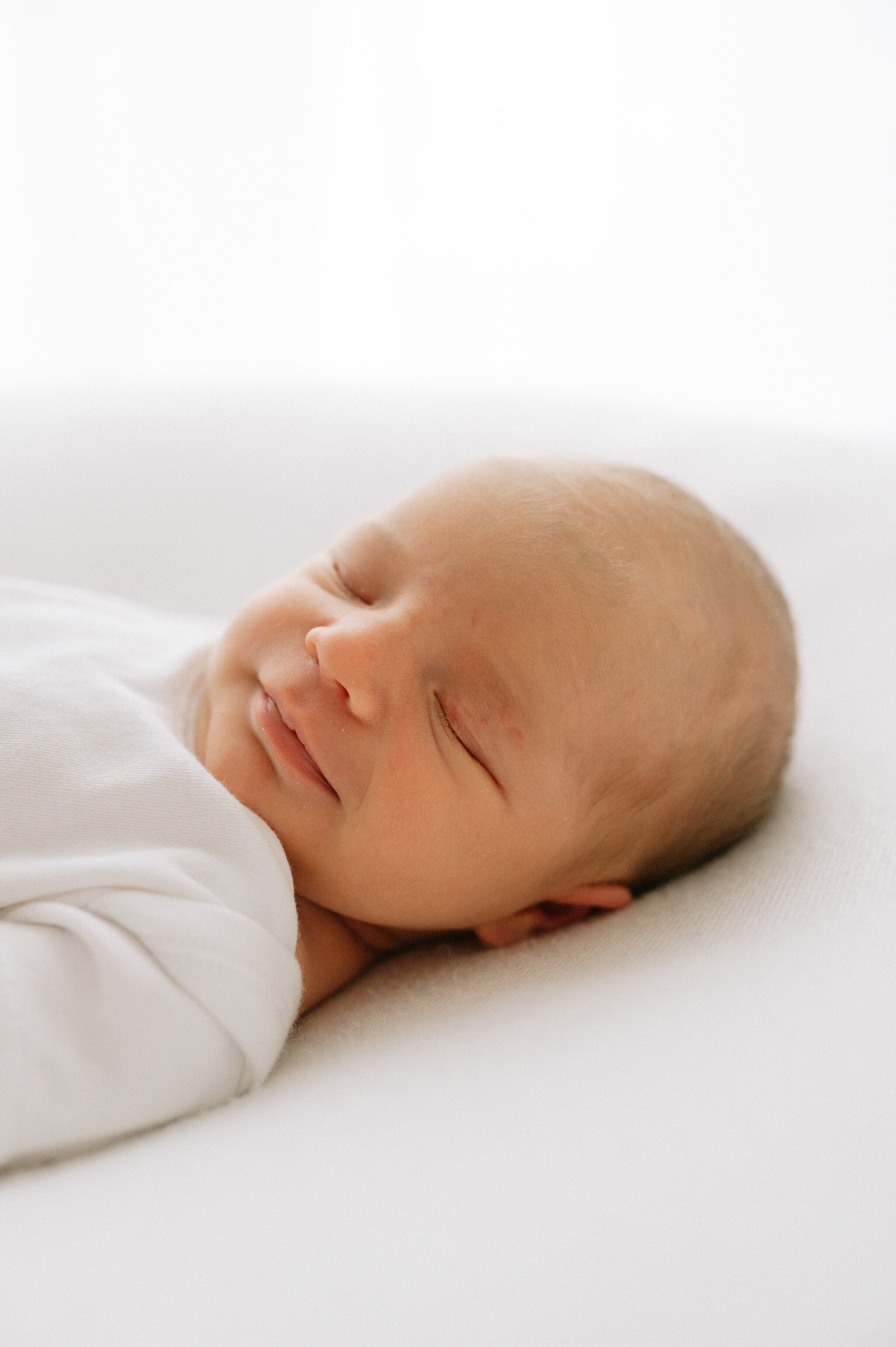 newborn baby girl smiling asleep in photography studio