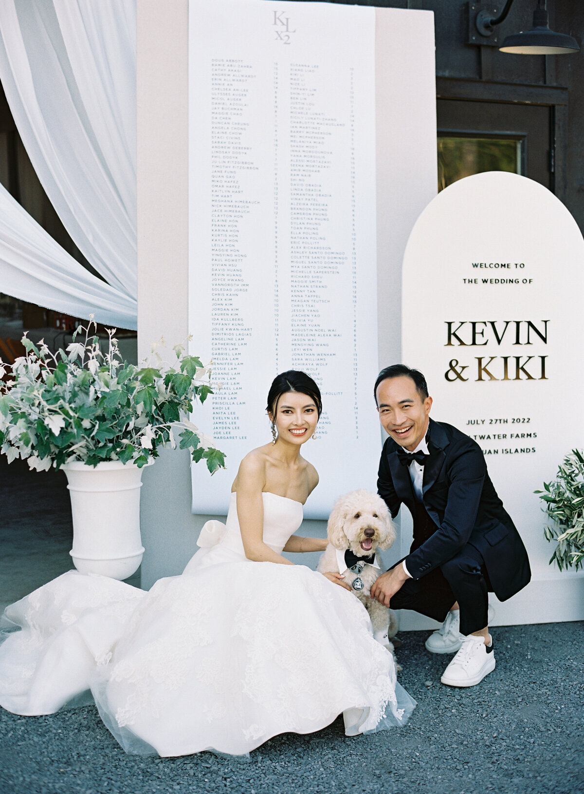 bride and groom pose with goldendoodle dog at cocktail hour