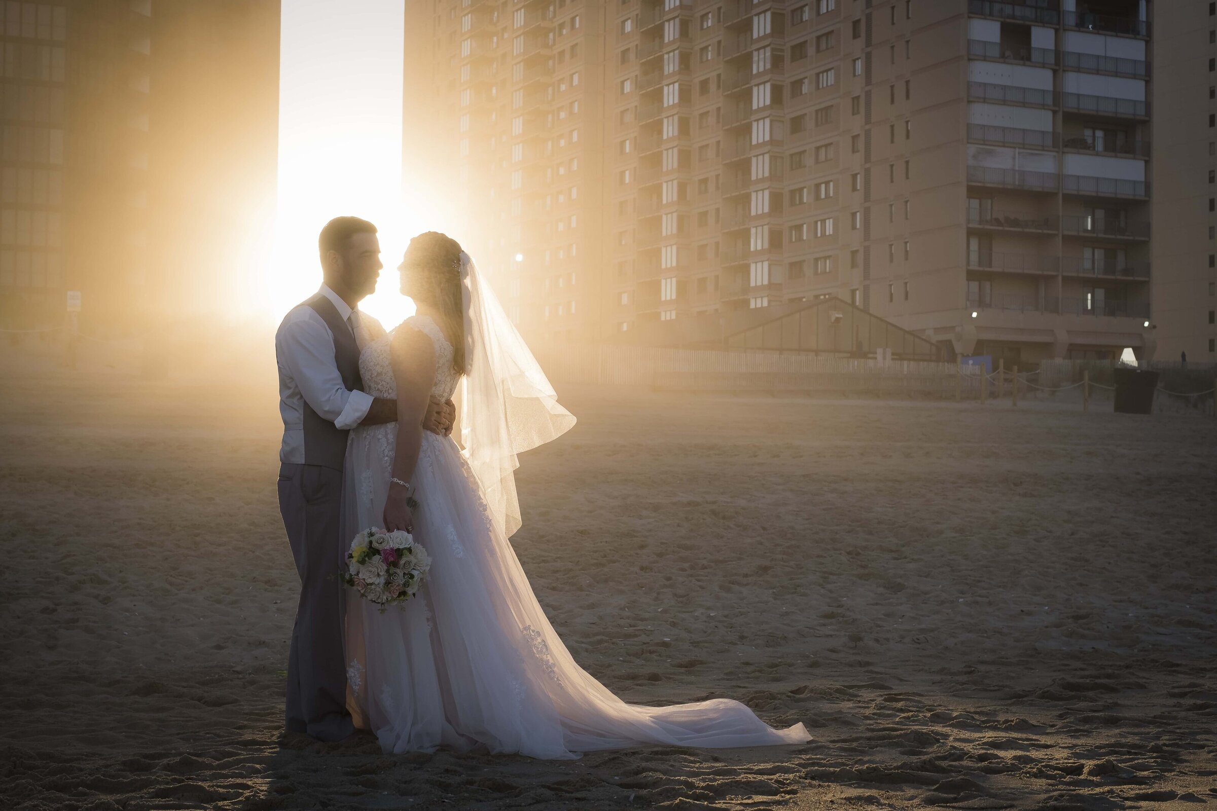backlit bride and groom portrait on beach
