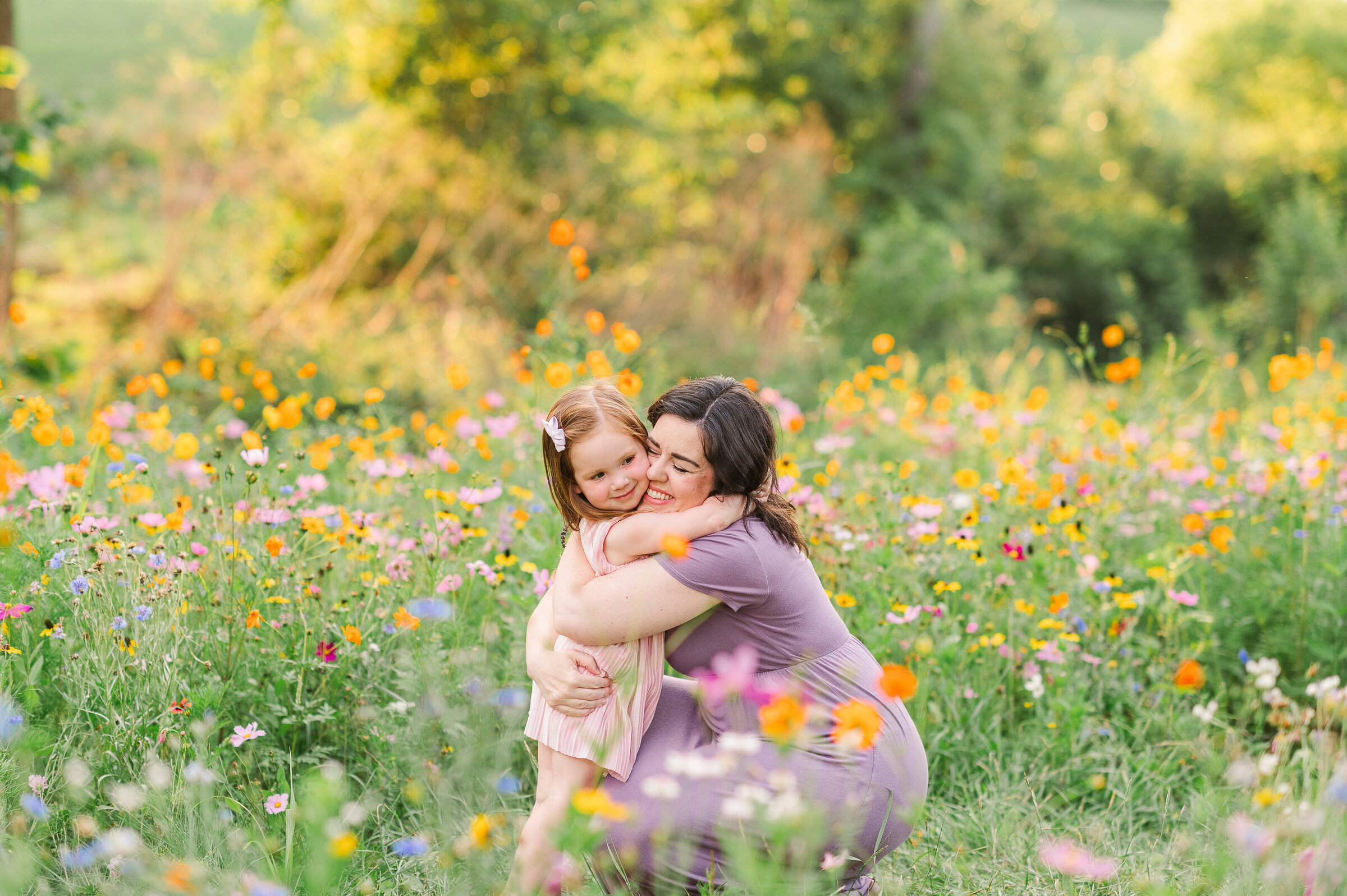 mother bending down hugging her daughter in a field of wildflowers by harrisburg pa photographer