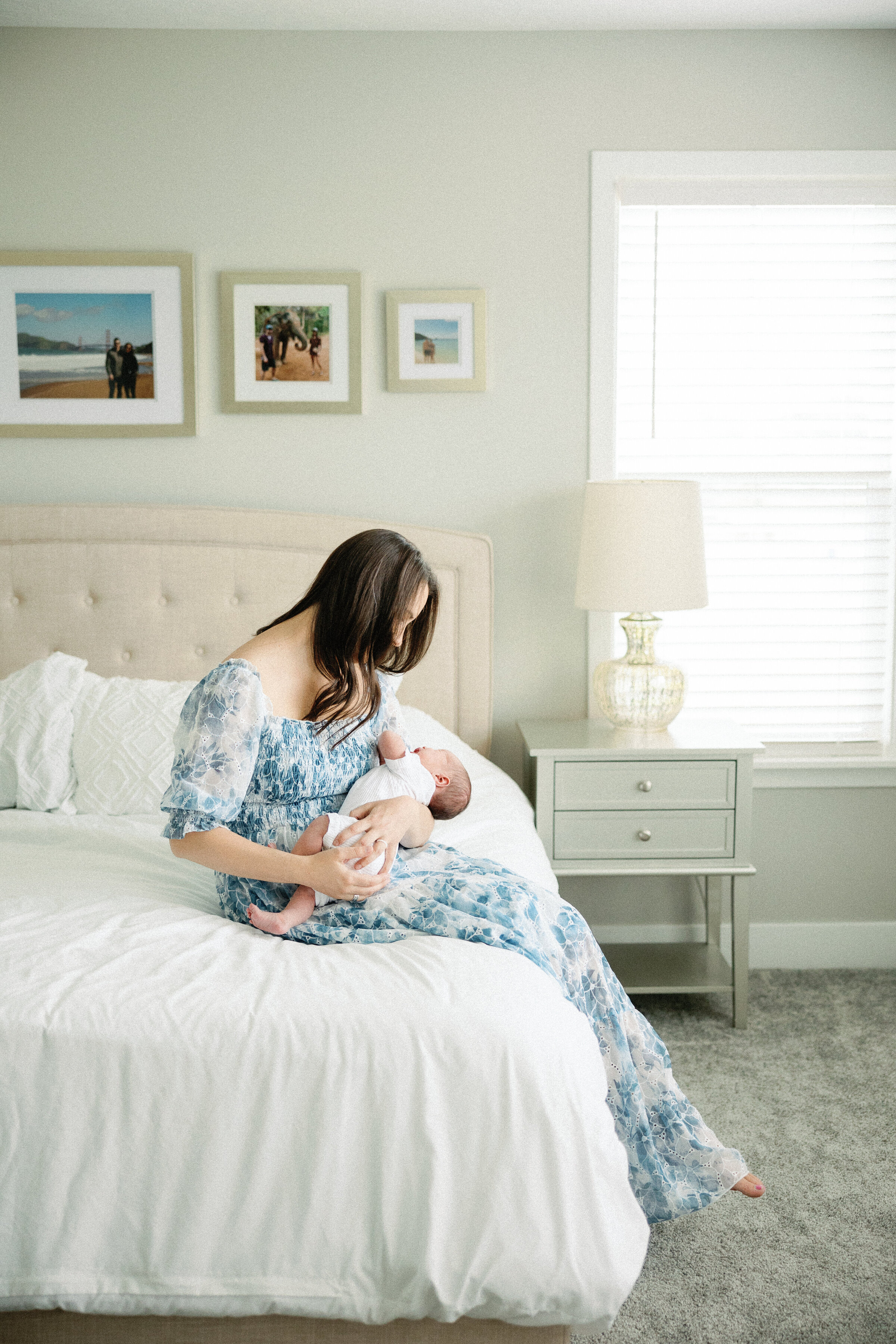 mother sitting on edge of bed holding baby