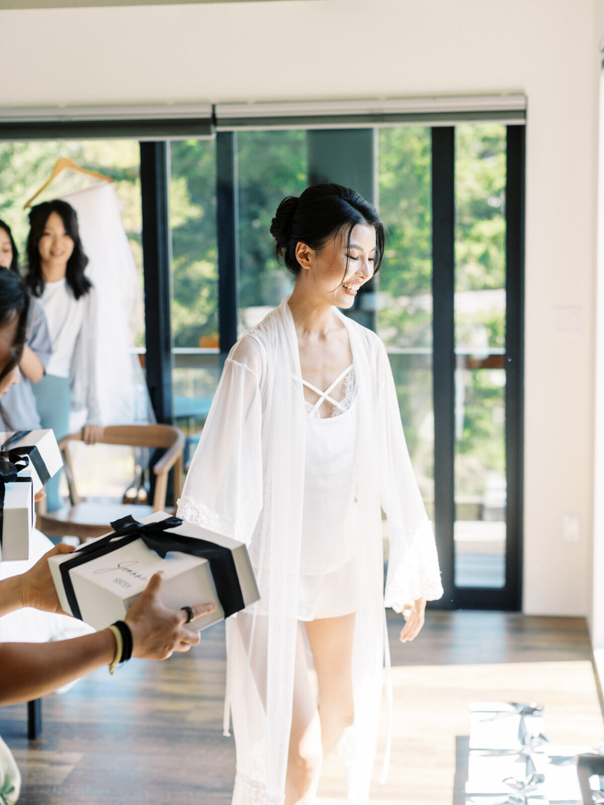 bride smiling in white silk robe while getting ready