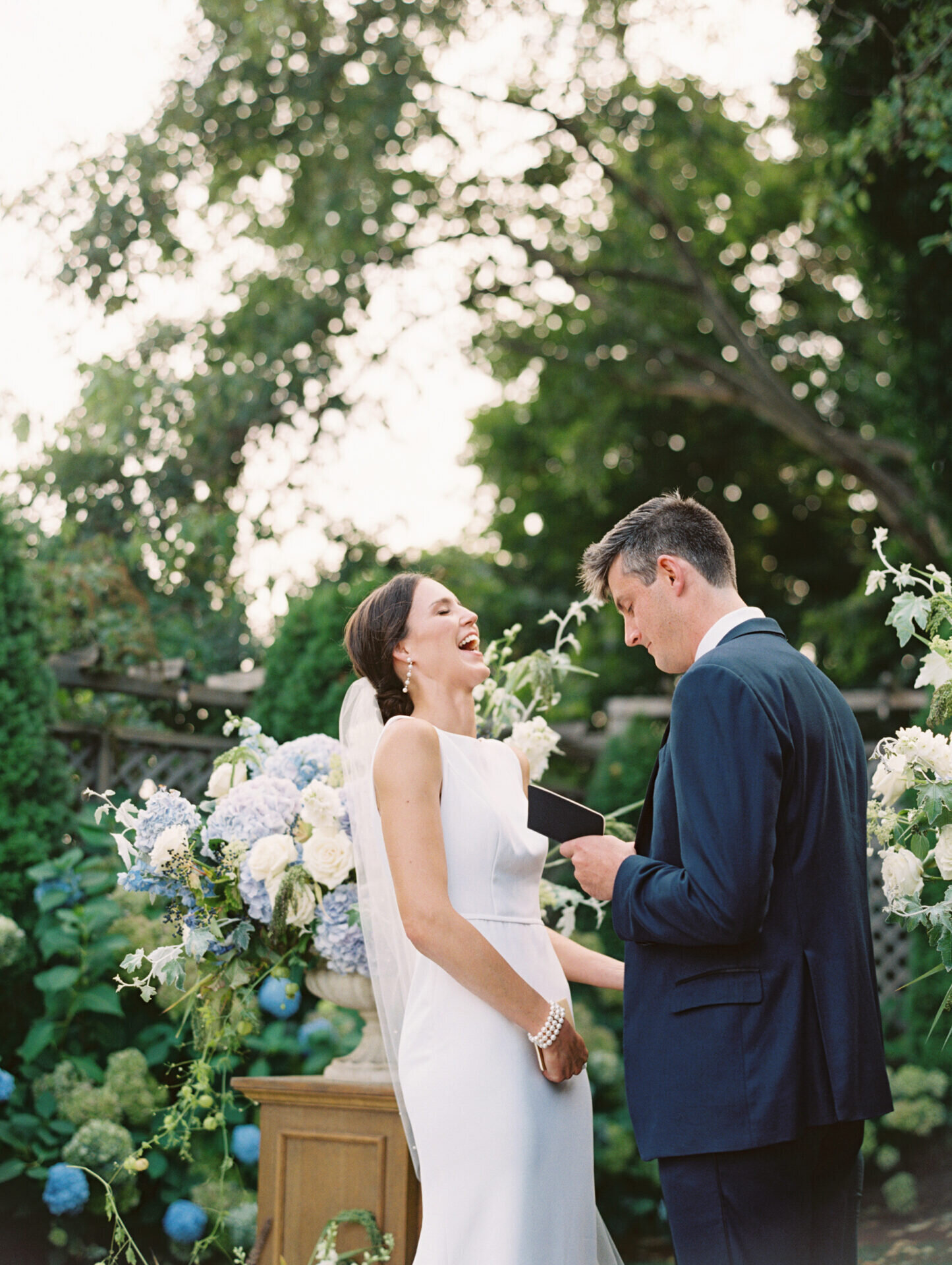 bride laughing during wedding ceremony with greenery in background