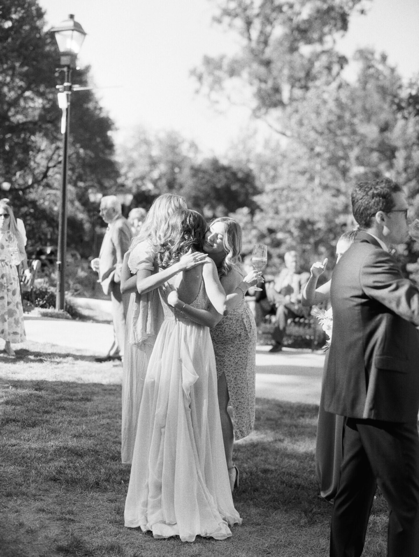 black and white film candid of bride hugging her guests at outdoor wedding